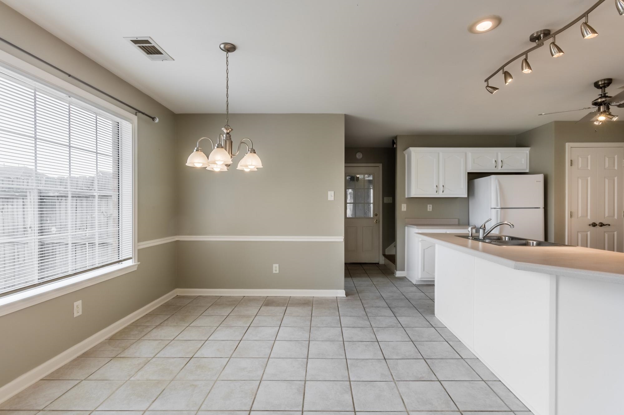 Kitchen and dining area with white cabinets, a breakfast bar, gray tile floors, and a large window.