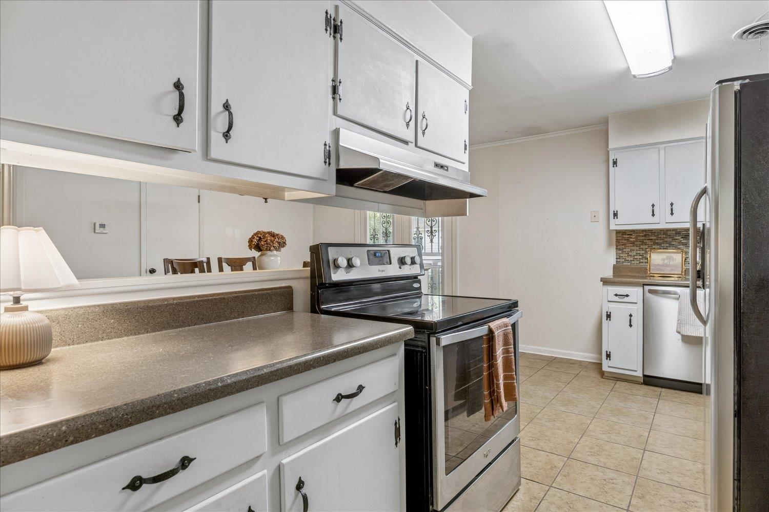 Kitchen with white cabinets, dark counters, and a black-and-stainless electric range.