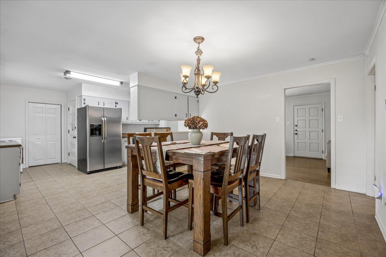 Kitchen and dining area with a large wooden table, white cabinets, and stainless steel refrigerator.