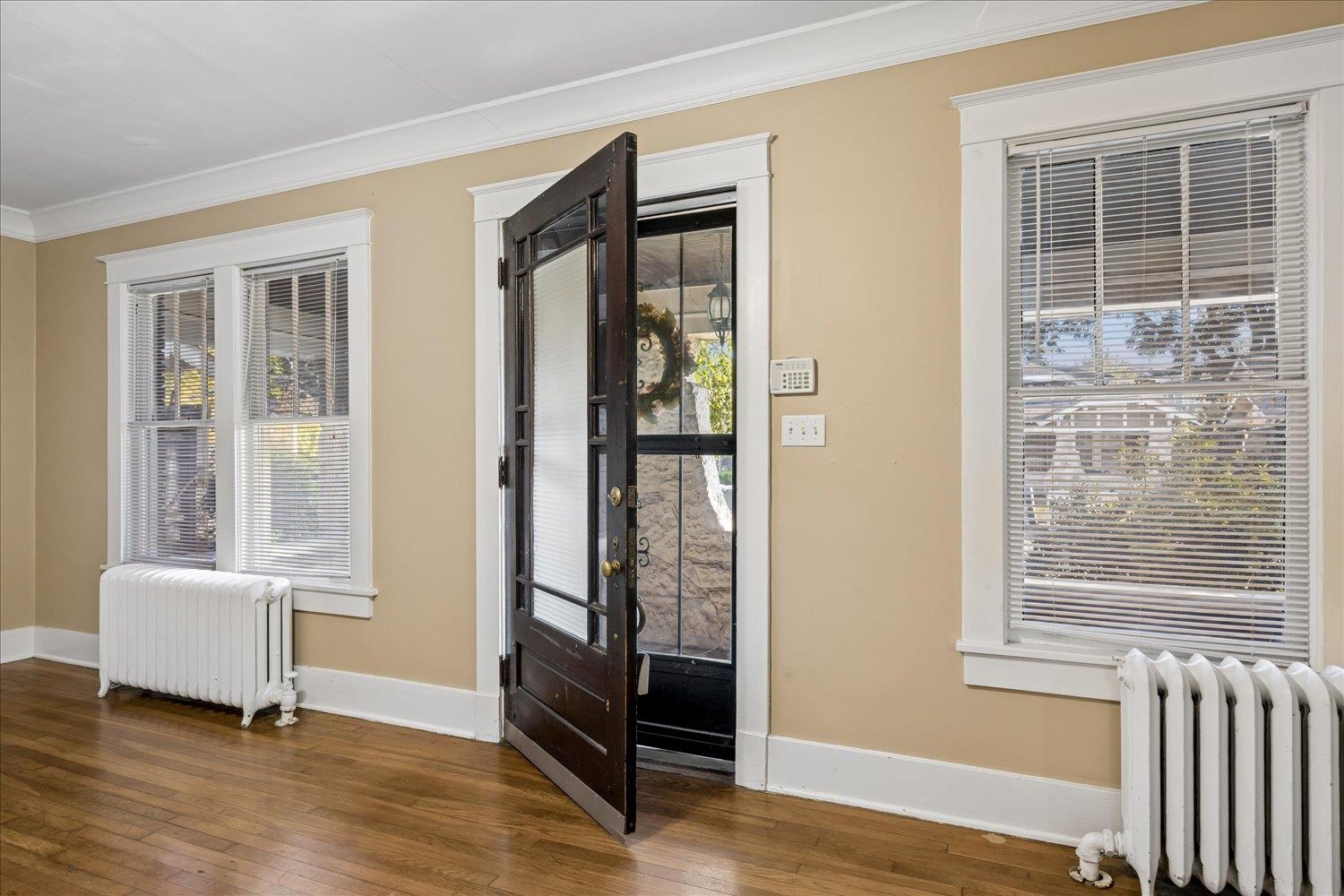 Entry area with hardwood floors, white radiators, and an open dark wood front door.