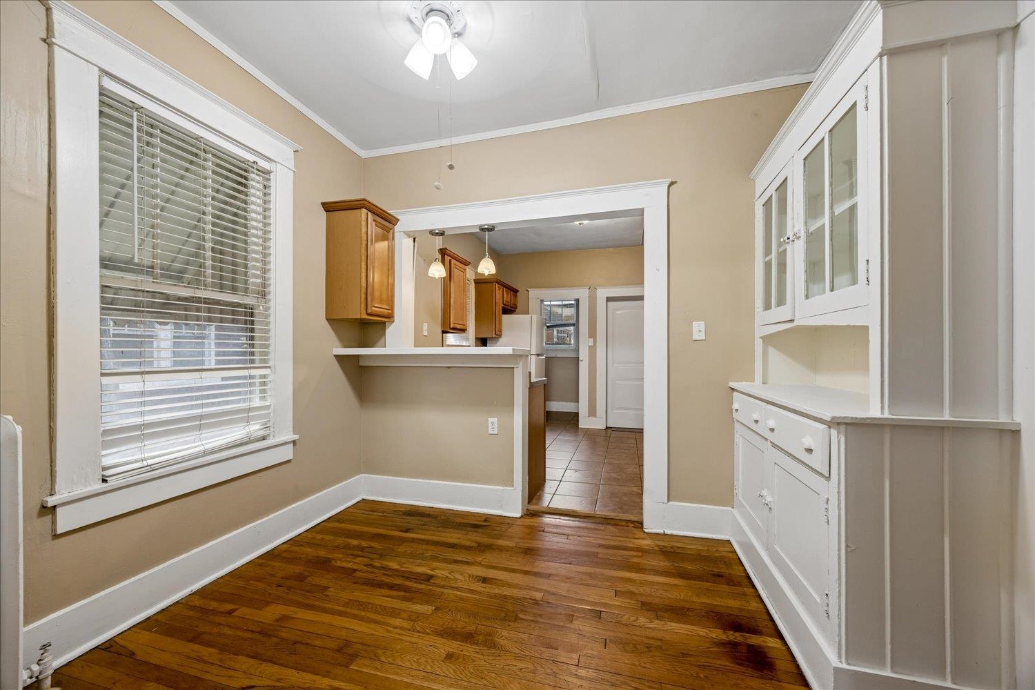 Dining room with hardwood floors and a built-in white hutch, opening onto the kitchen.