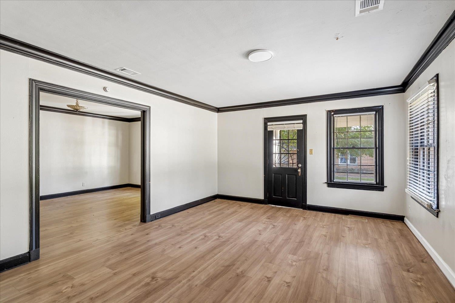 Vacant room with wood-look flooring, black trim, and a glass-paneled exterior door.