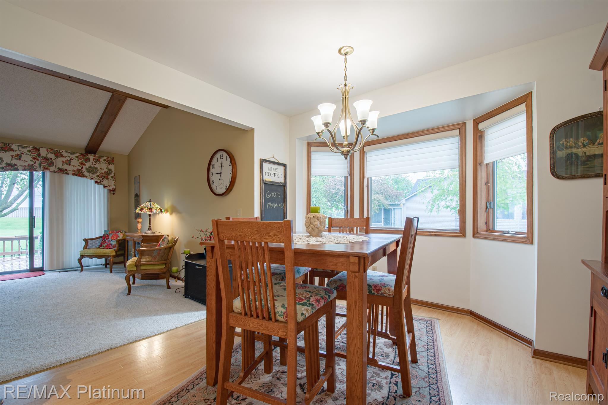 Dining area with a wooden table, chandelier, and large wood-trimmed windows.