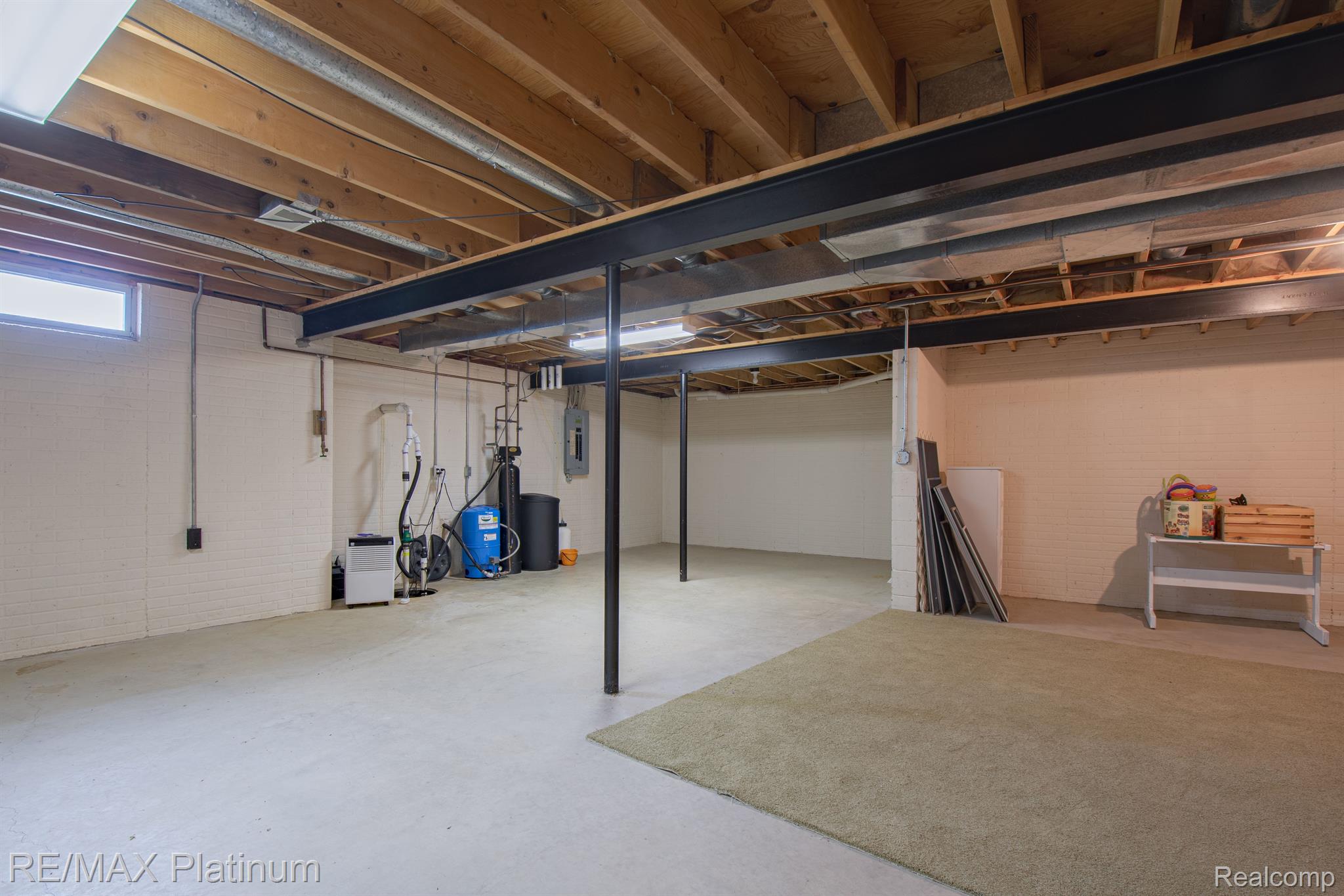 Open basement with exposed ceiling joists, steel support beams, and utility equipment.