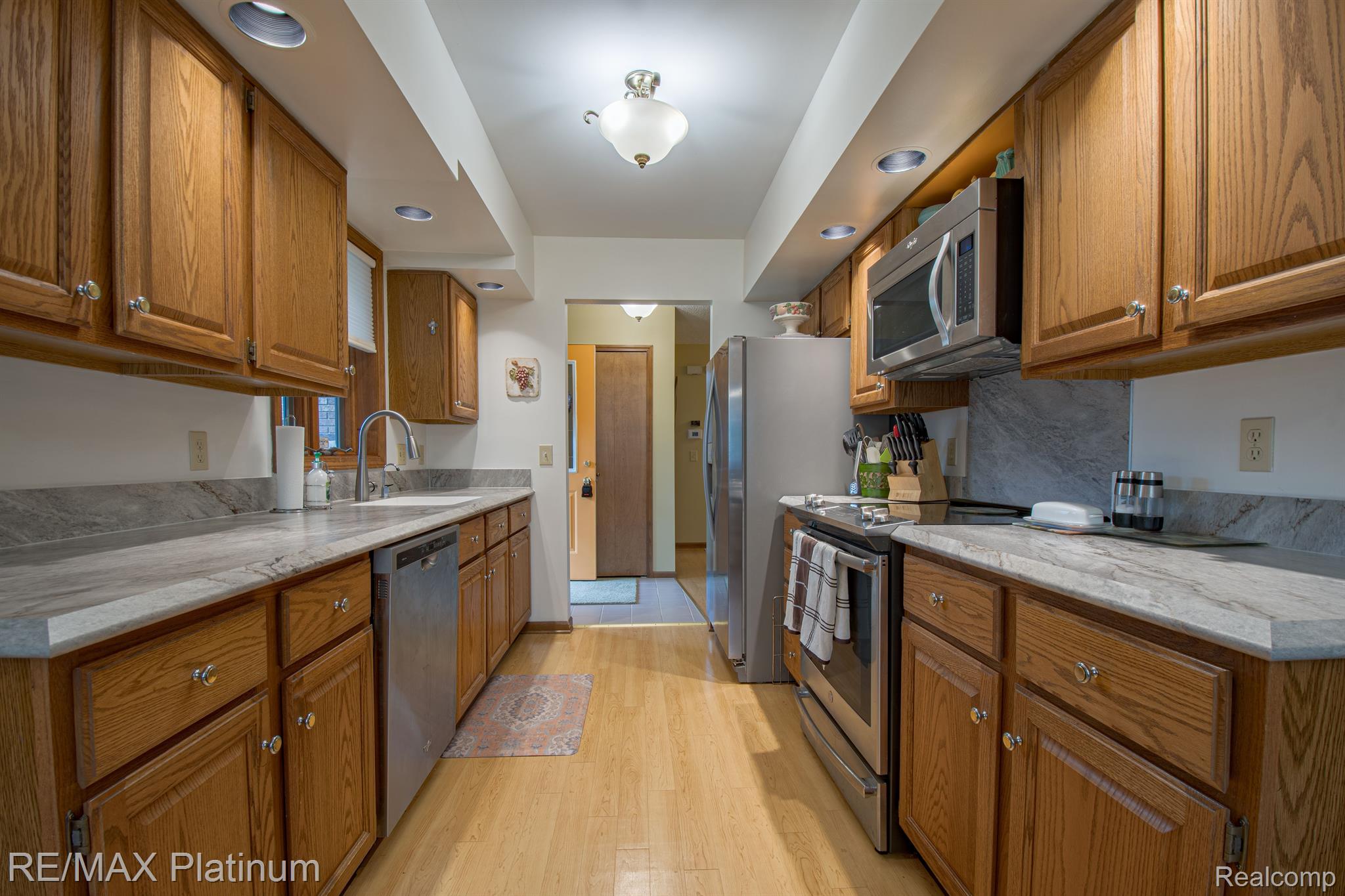 Galley kitchen with oak cabinets, gray countertops, and stainless steel appliances.