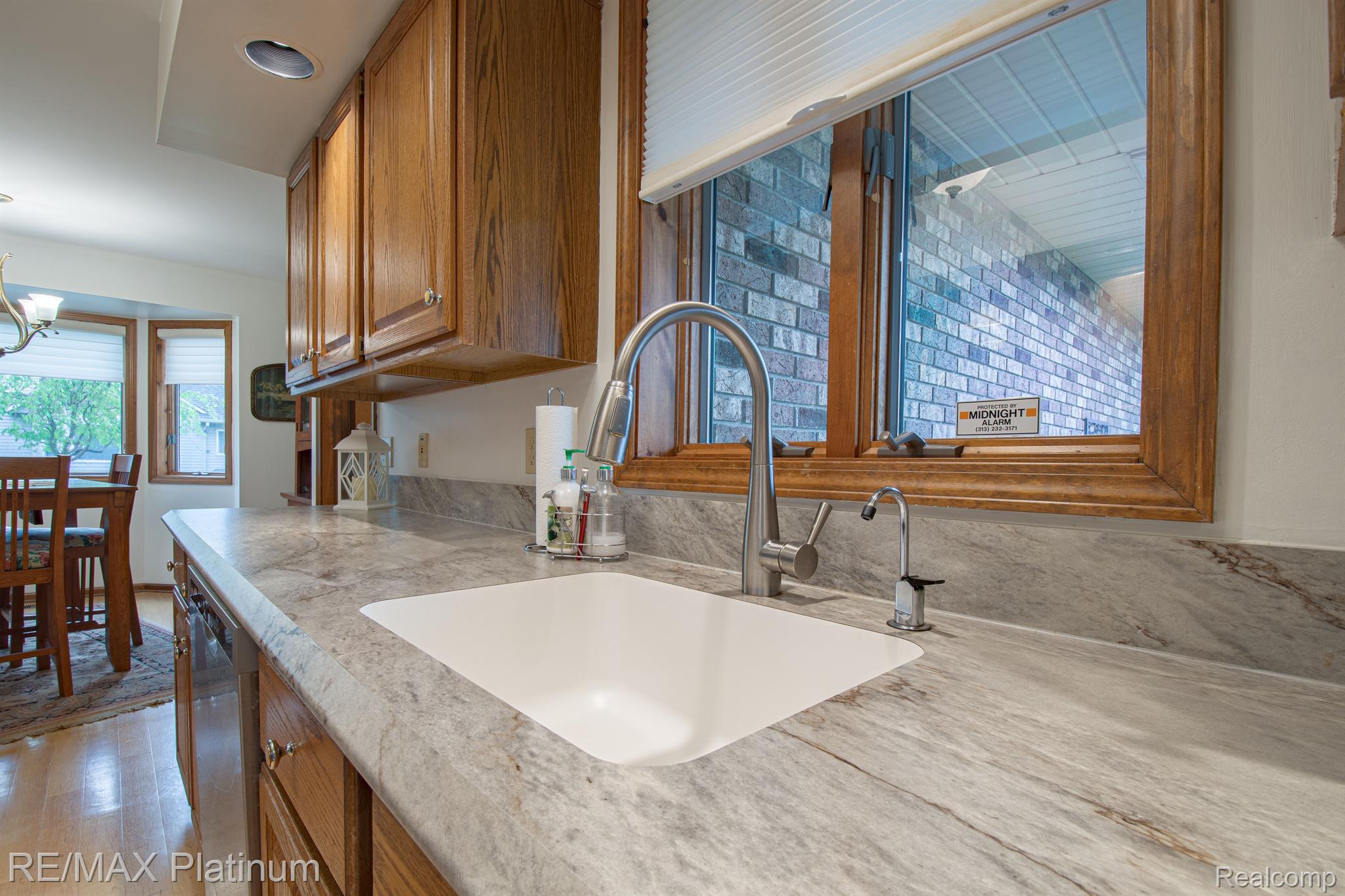 Kitchen with a broad stone-pattern countertop, undermount sink, and wood-framed window.