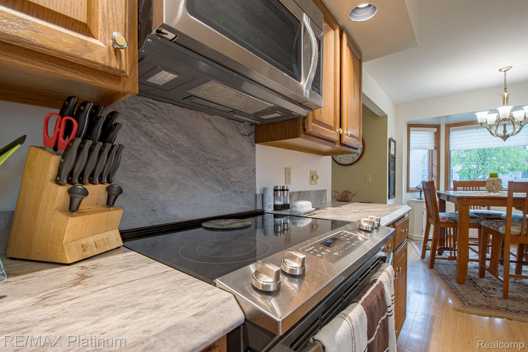 Kitchen with wood cabinets, stone counters, and stainless-steel range opening to a dining area.