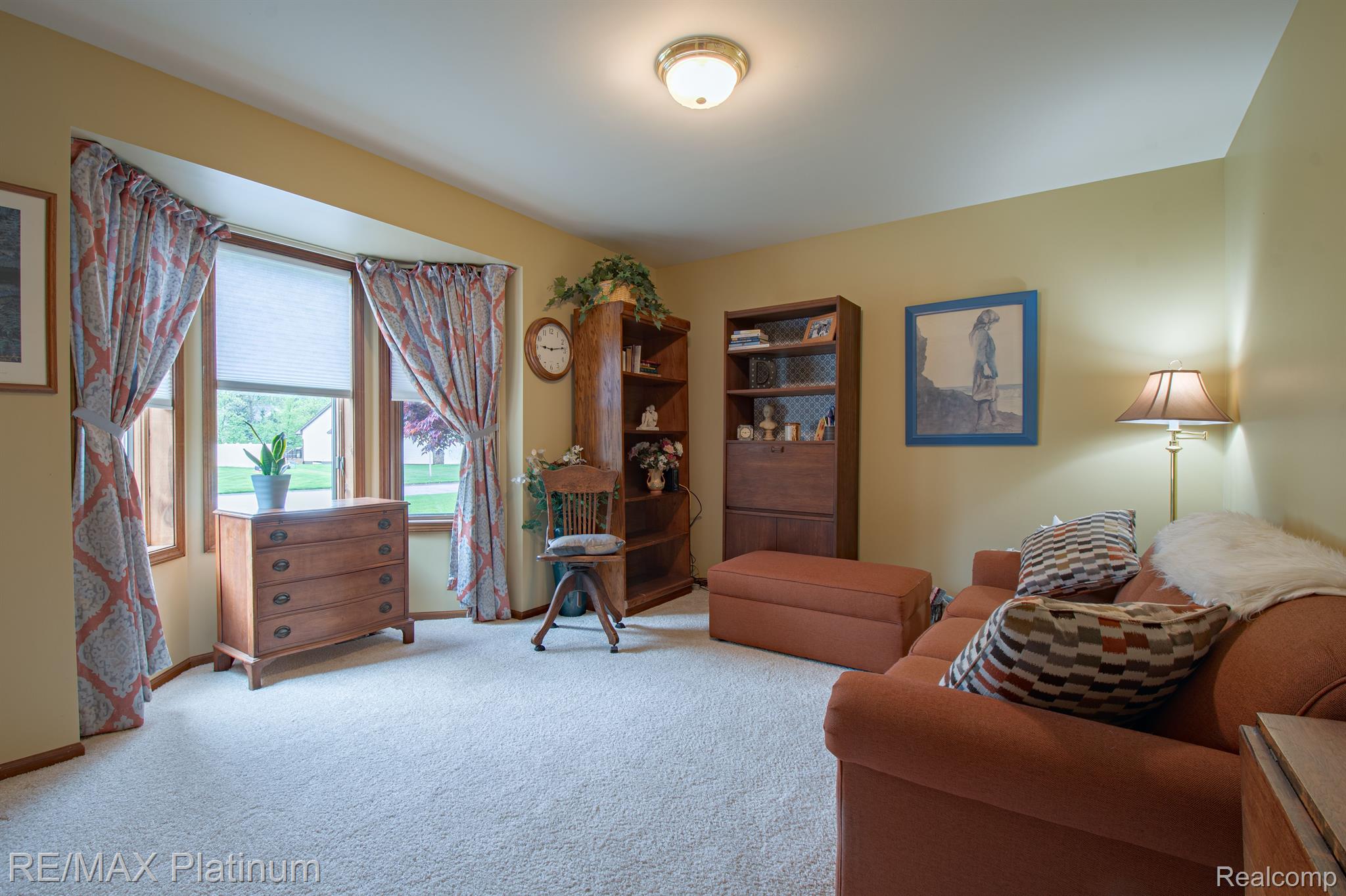 Living room with a rust-colored sectional sofa, wood bookcases, and curtained windows.