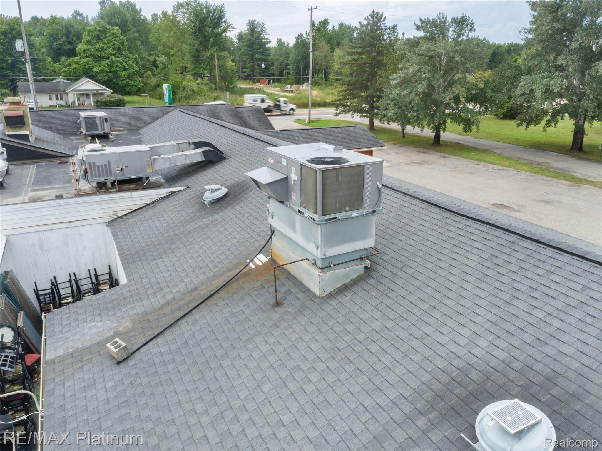 Large shingle roof with multiple rooftop HVAC units and vents.