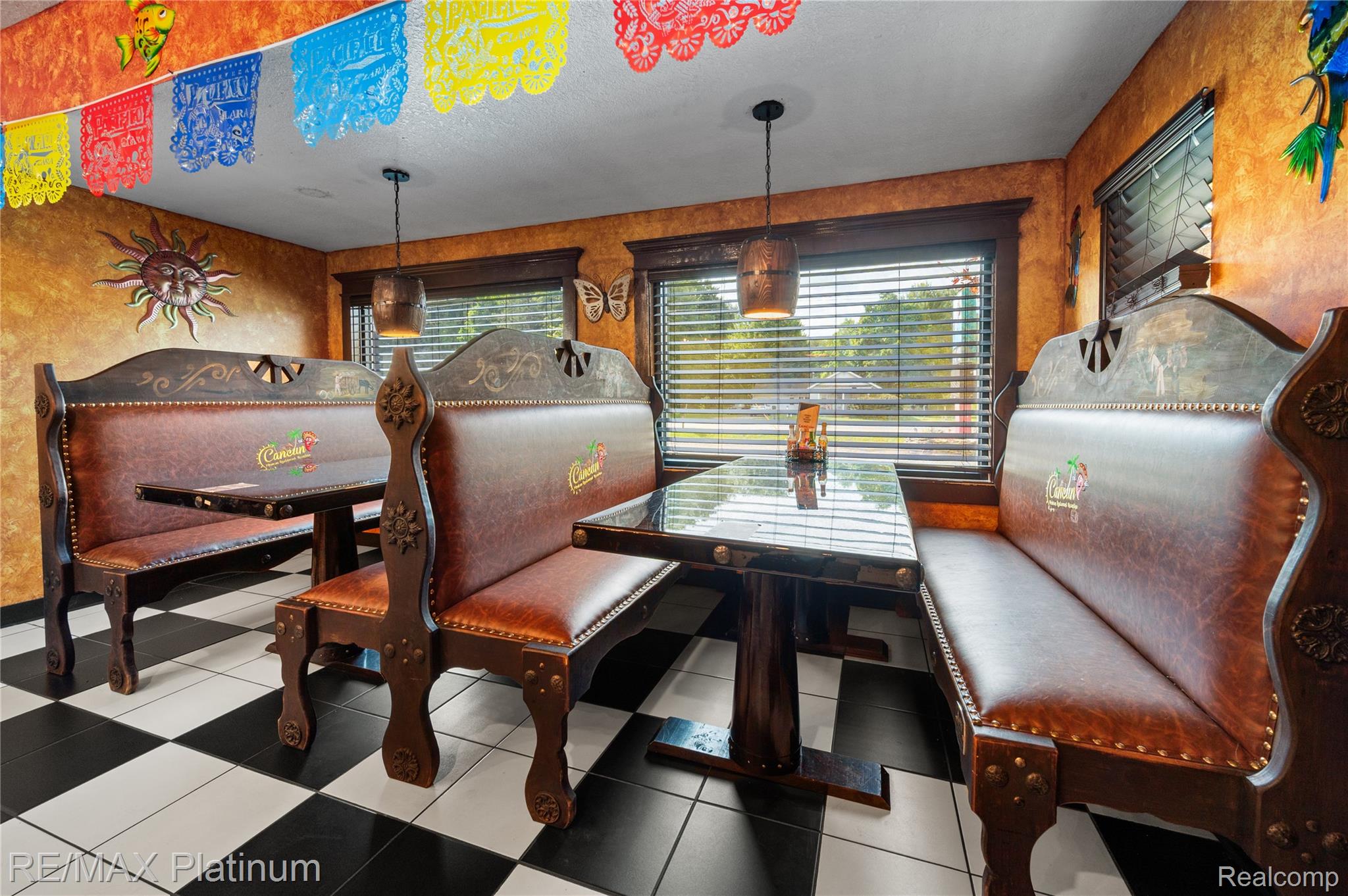 Dining area with ornate brown leather booths, glossy tables, and black-and-white tile flooring.