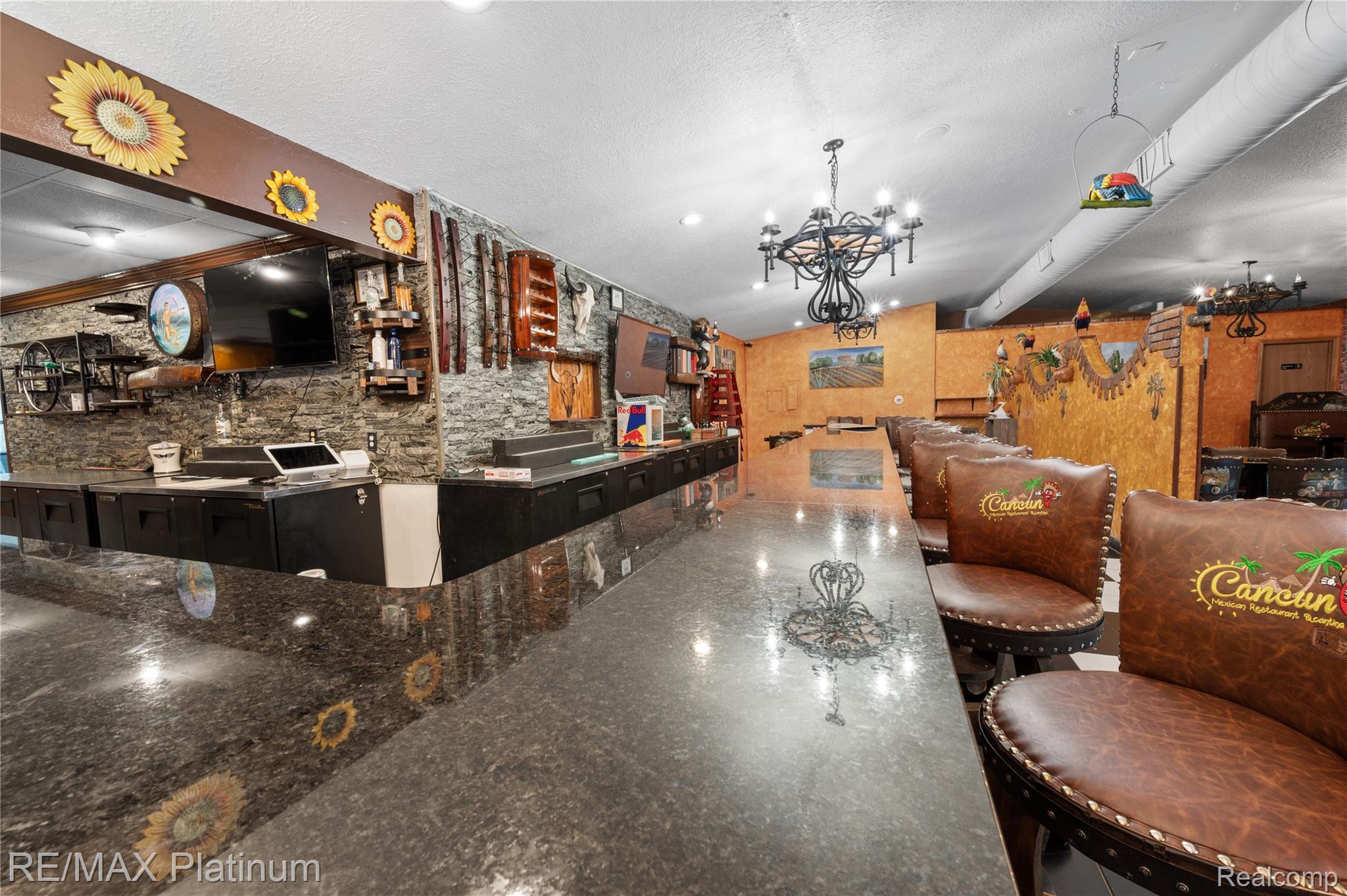 Restaurant bar with a polished stone counter, leather stools, and Southwestern-style decor.