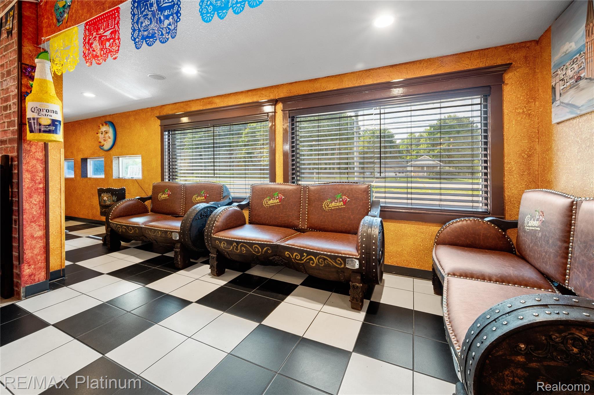 Waiting area with Cancun-branded leather seating, orange walls, and black-and-white checkerboard flooring.