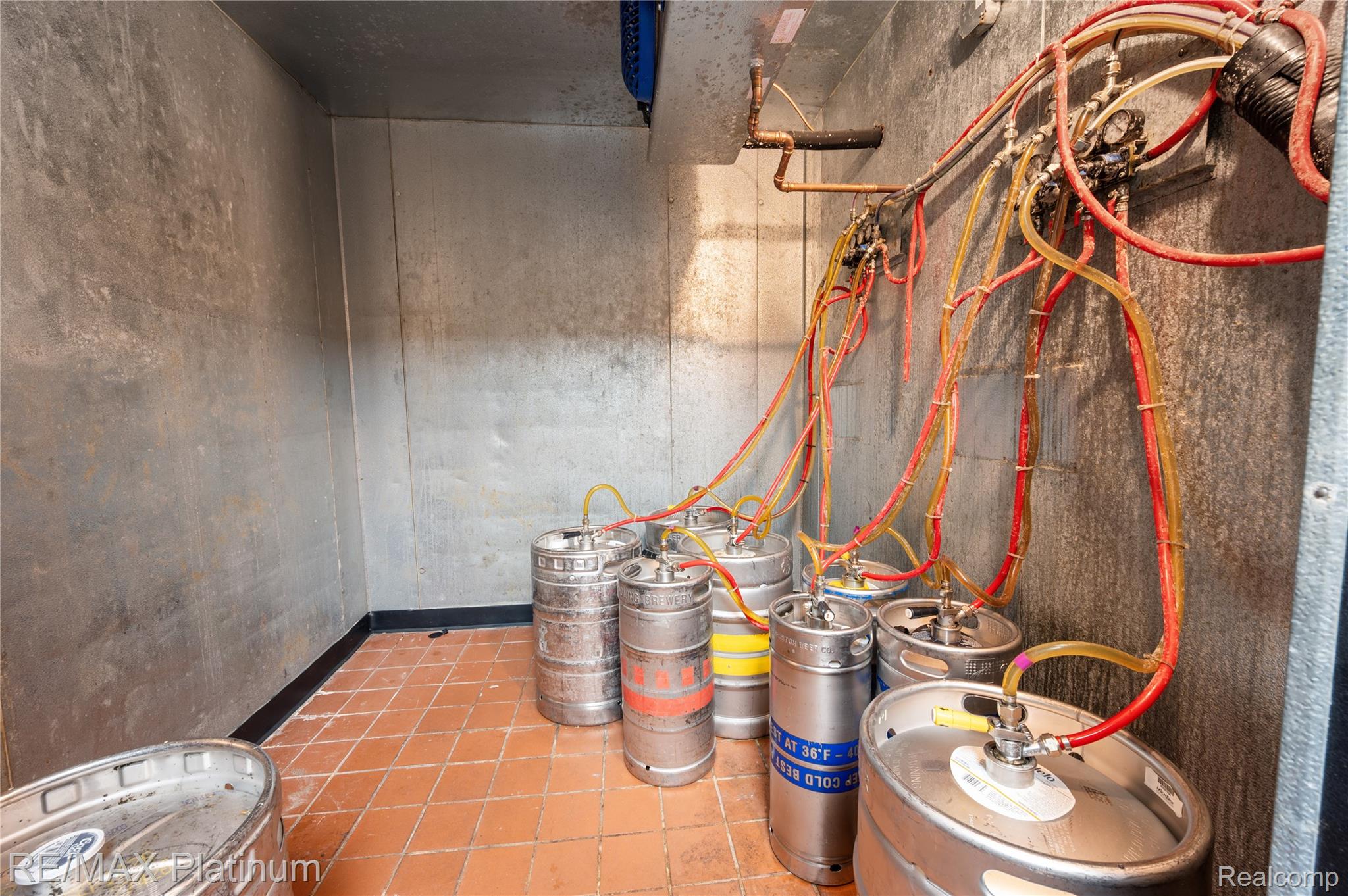 Keg room with metal beer kegs connected to colorful beverage lines.