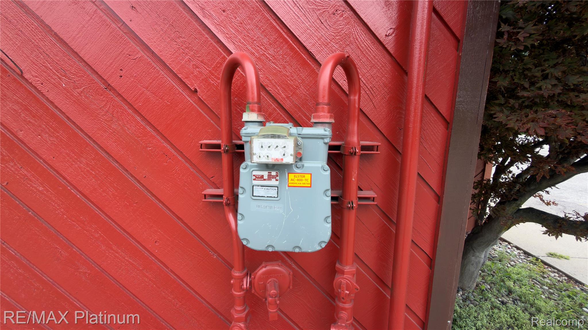 Gas meter and red pipes mounted on diagonal red siding.