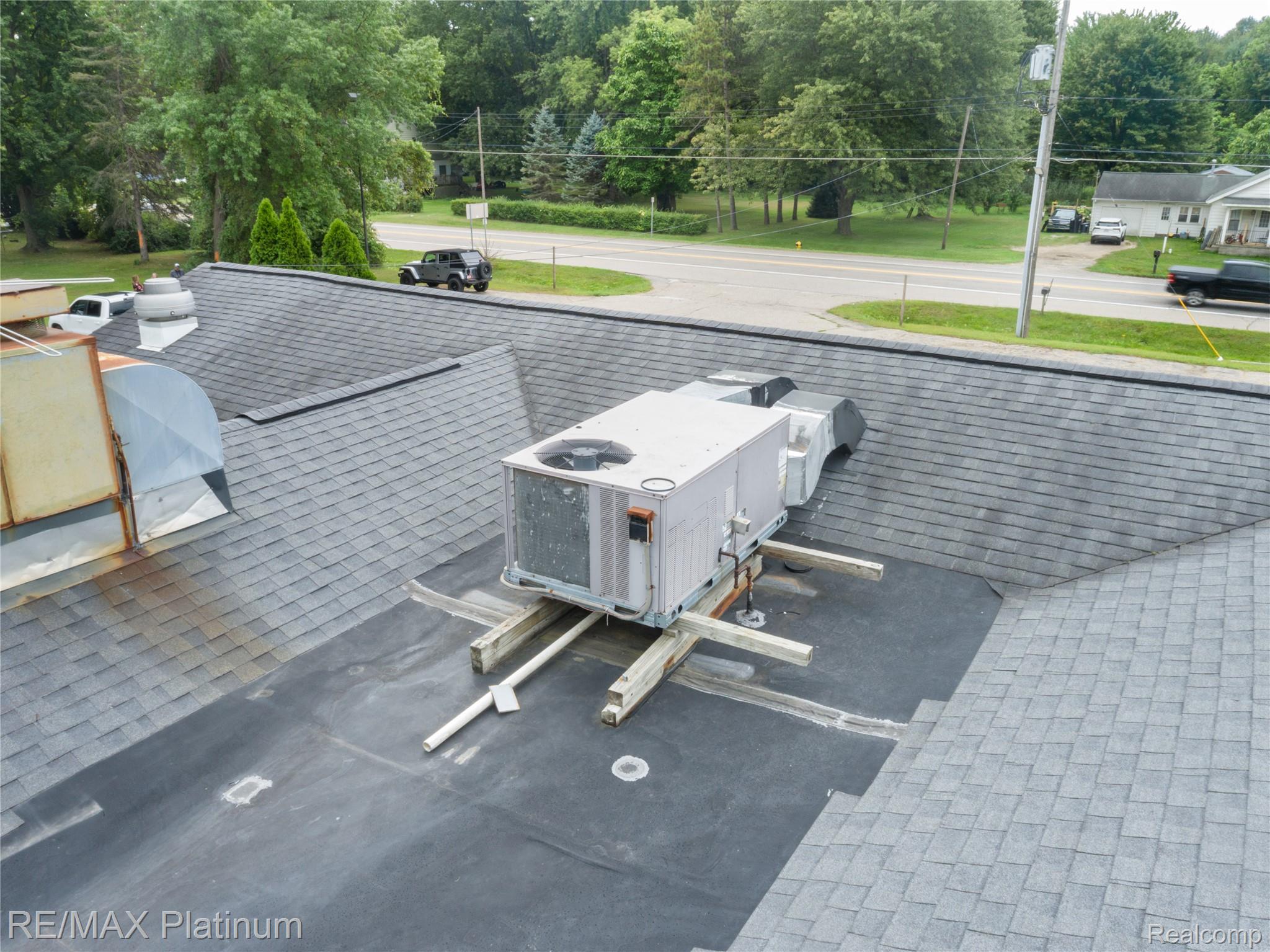 Gray shingle roof with a large rooftop HVAC unit and metal vents.