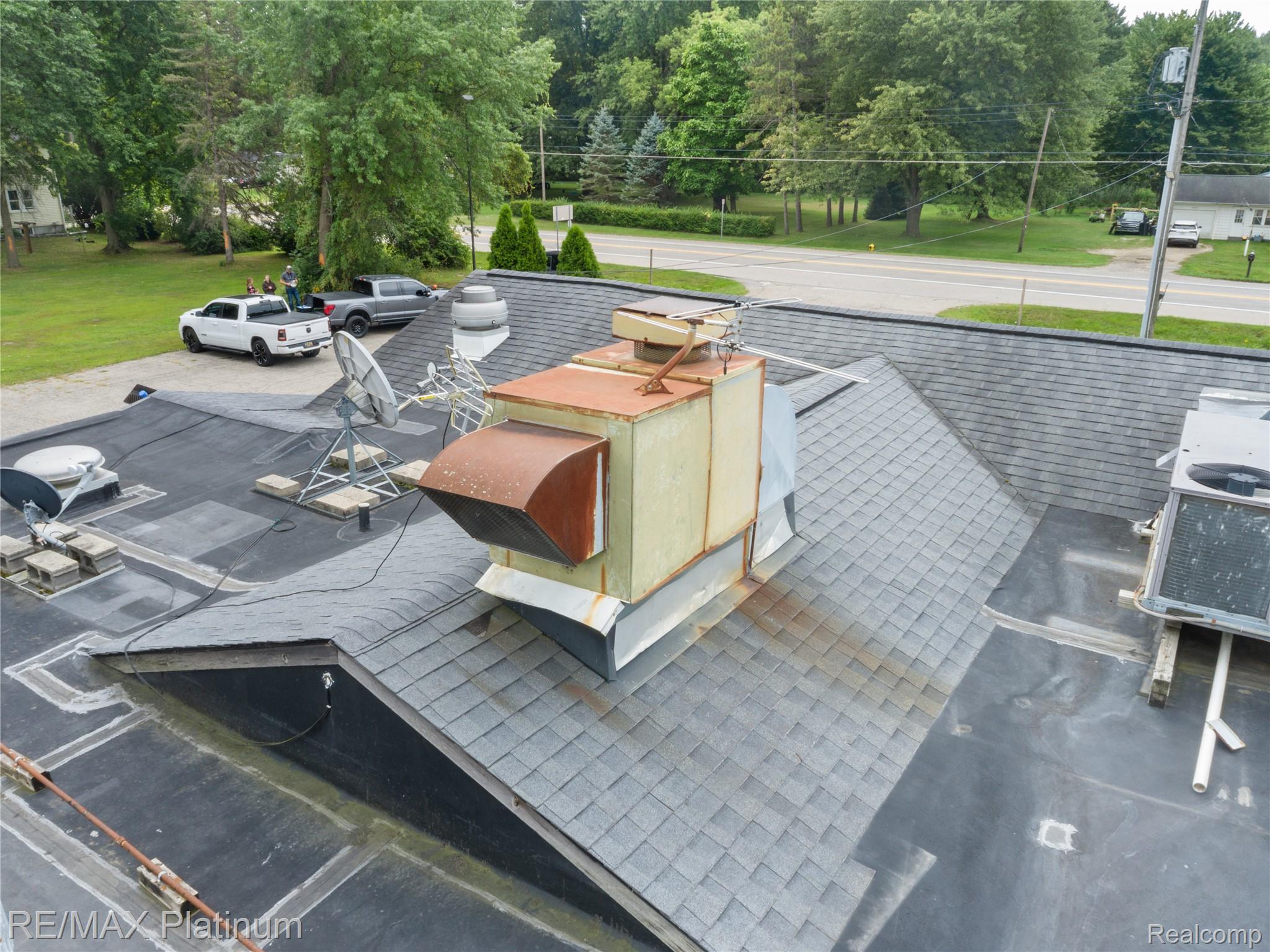 Commercial building roof with large rust-stained ventilation equipment, satellite dishes, and antennas.