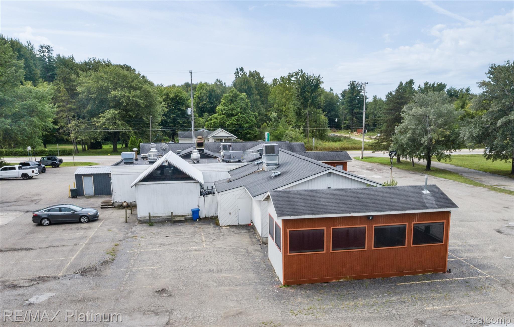 Commercial property with connected low-rise buildings, a paved parking lot, and trees behind it.