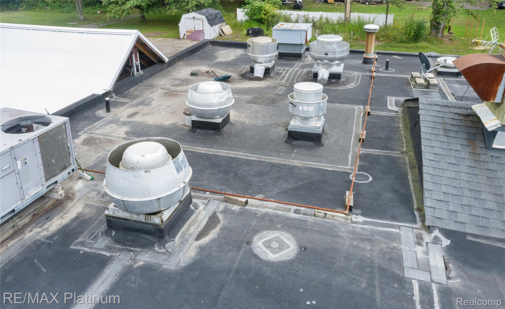 Flat commercial roof with multiple rooftop ventilation fans and HVAC units.