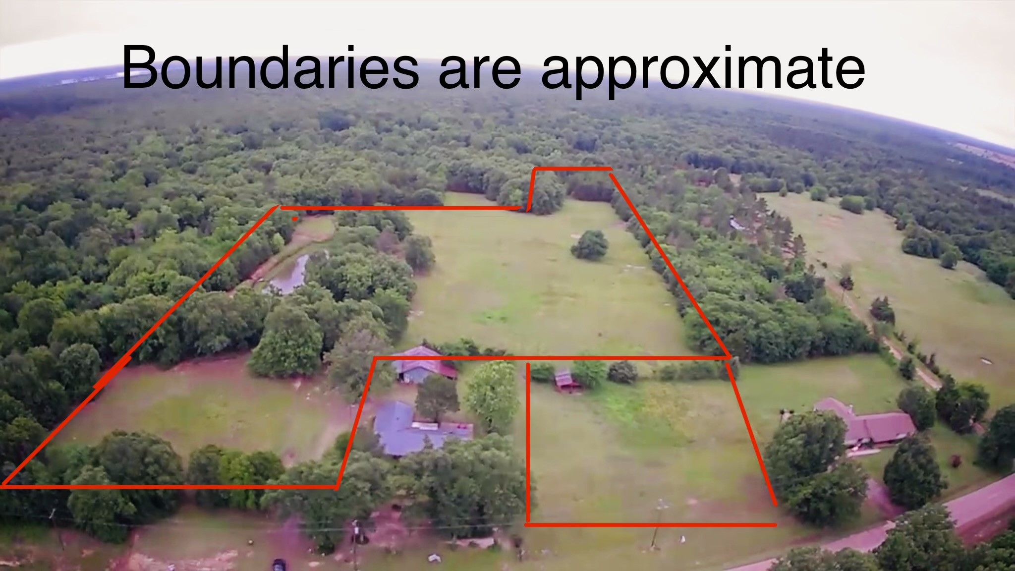 Aerial view of wooded acreage and open pasture, outlined with approximate property boundaries.