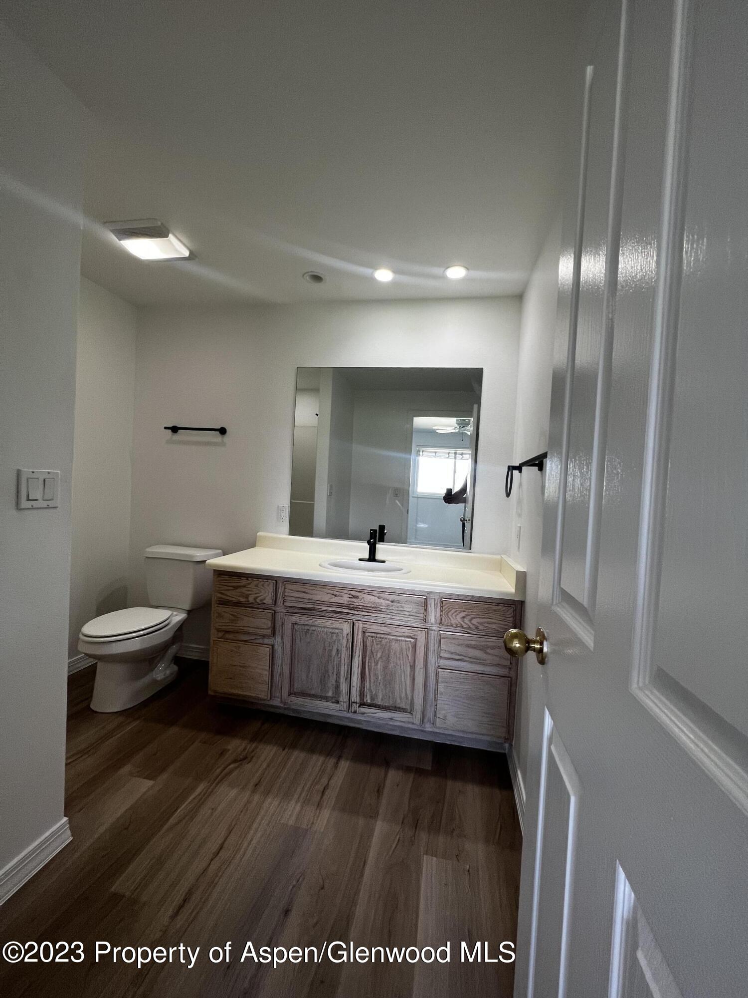 Bathroom with wood-look floors, weathered wood vanity, white countertop, and black faucet.