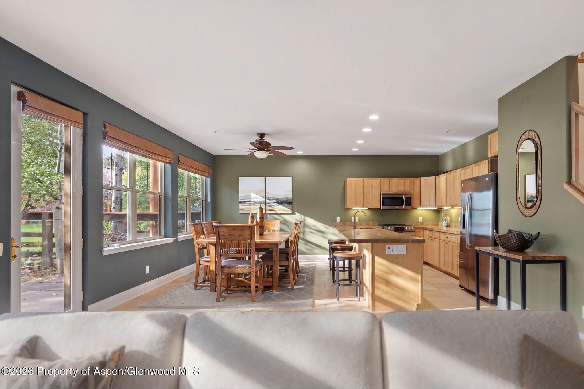 Open kitchen and dining area with a wood island, stainless steel appliances, and large windows.