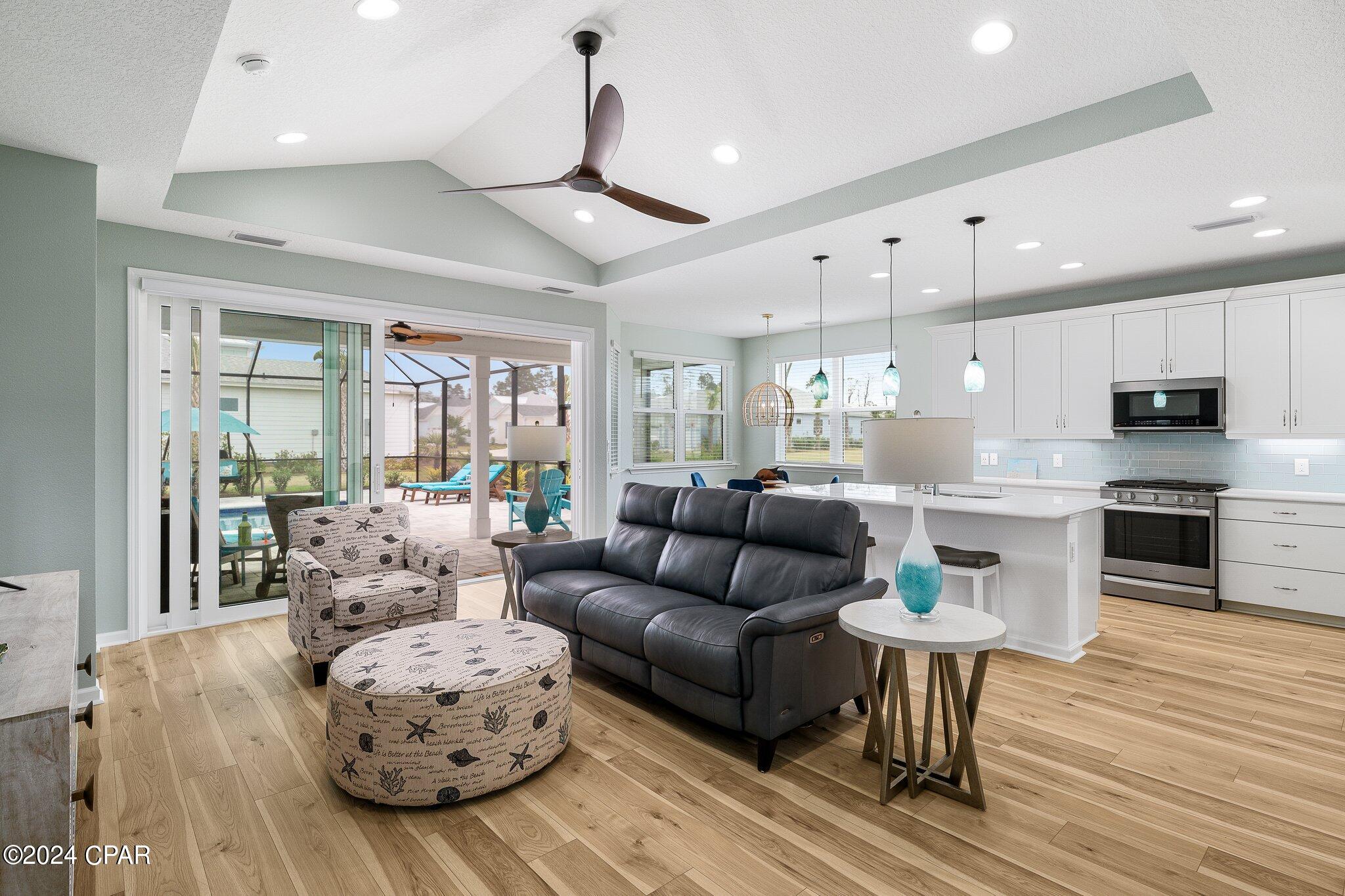 Open-plan living room and kitchen with sliding doors leading to a covered patio and pool.