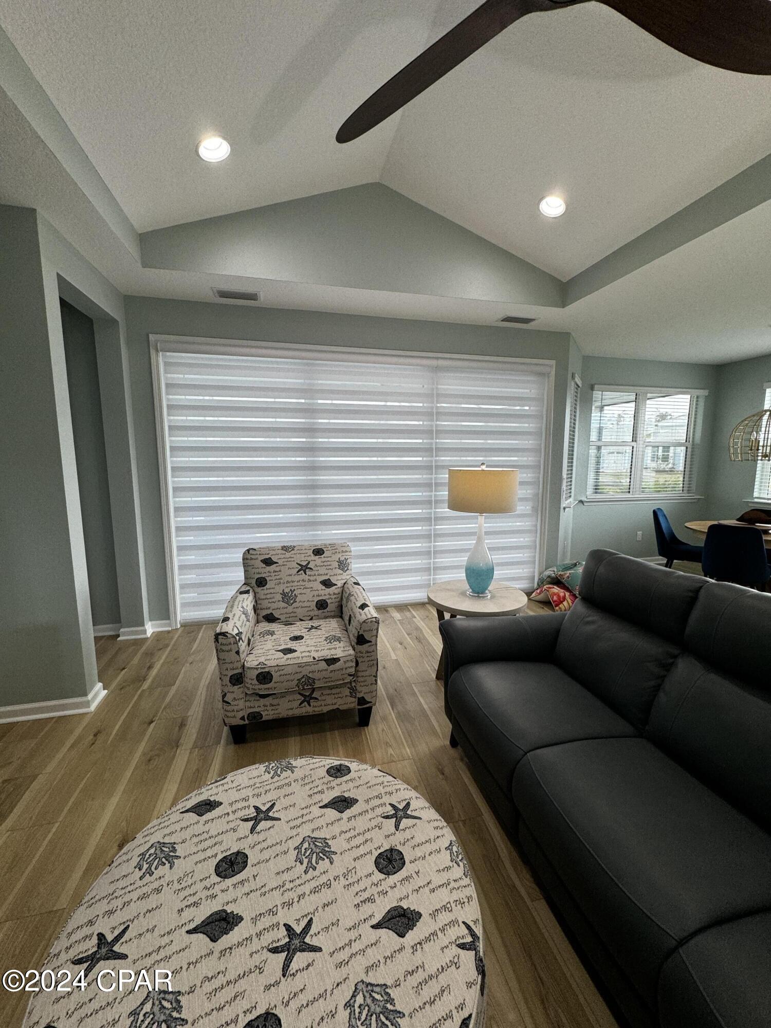 Living room with a gray sofa, coastal-patterned armchair, and vaulted ceiling.