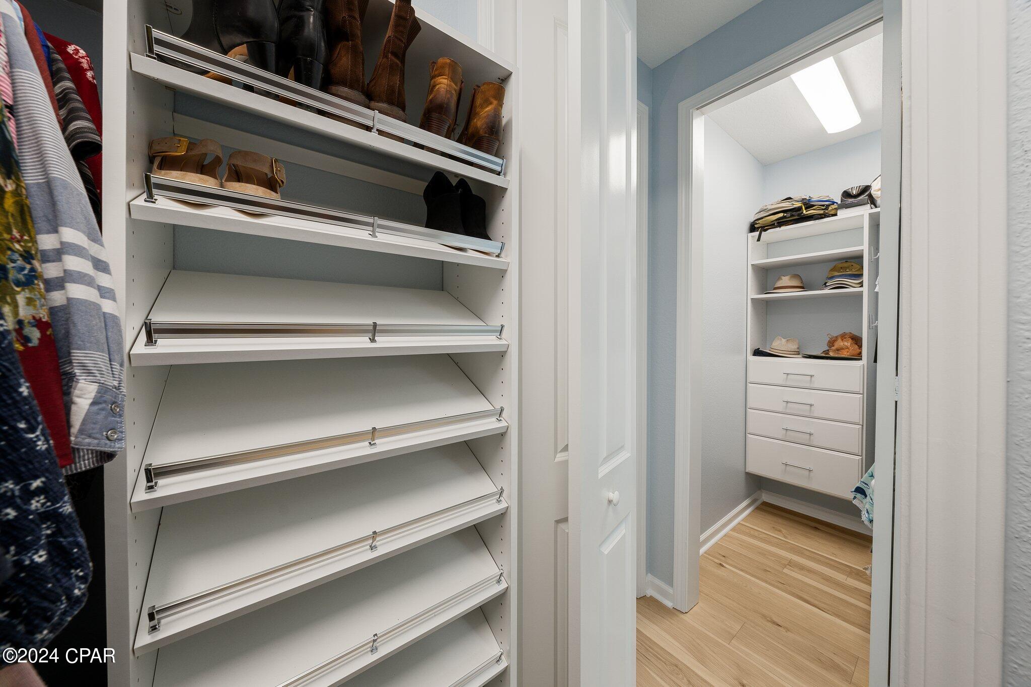 Walk-in closet with built-in shoe shelves and a second storage area with drawers and hats.
