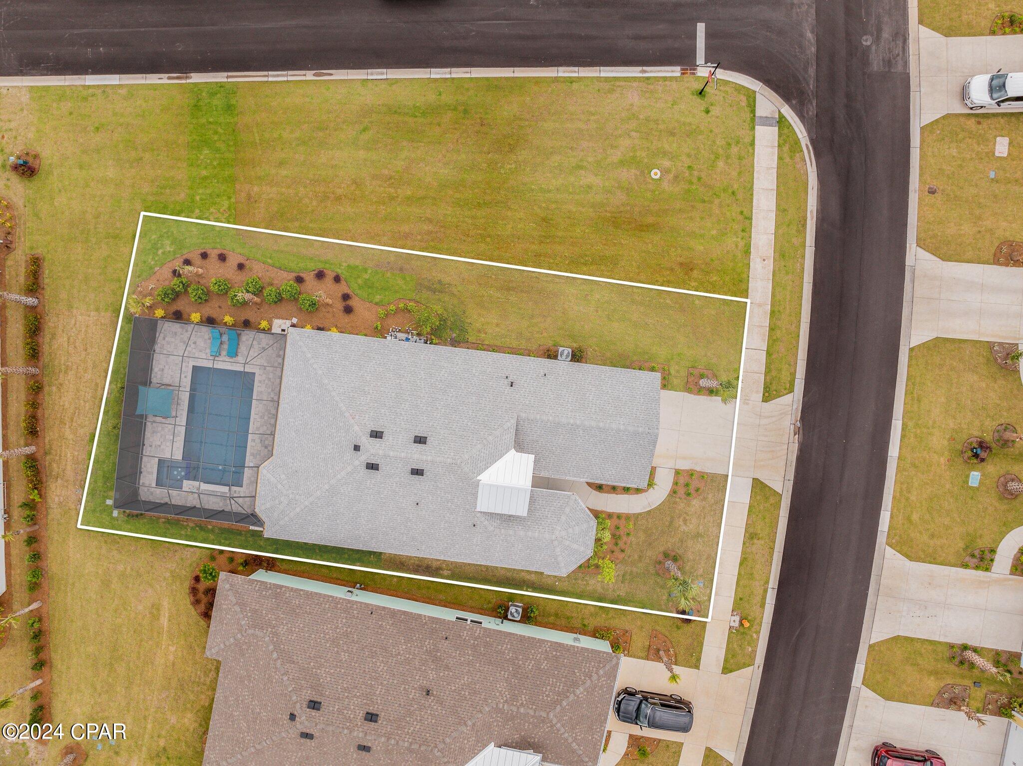 Aerial view of a home and outlined lot with a screened pool and landscaped yard.