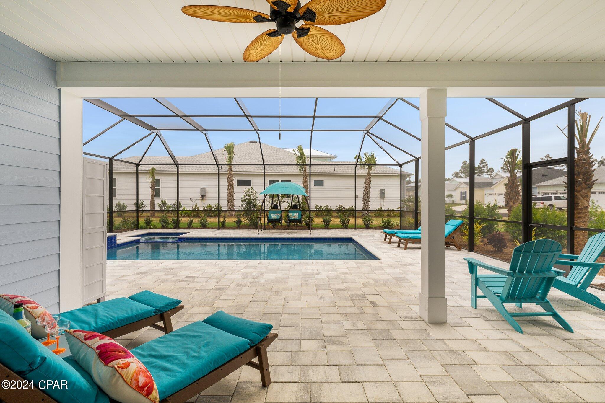 Screened pool patio with turquoise lounge chairs, a hanging swing, and a ceiling fan.