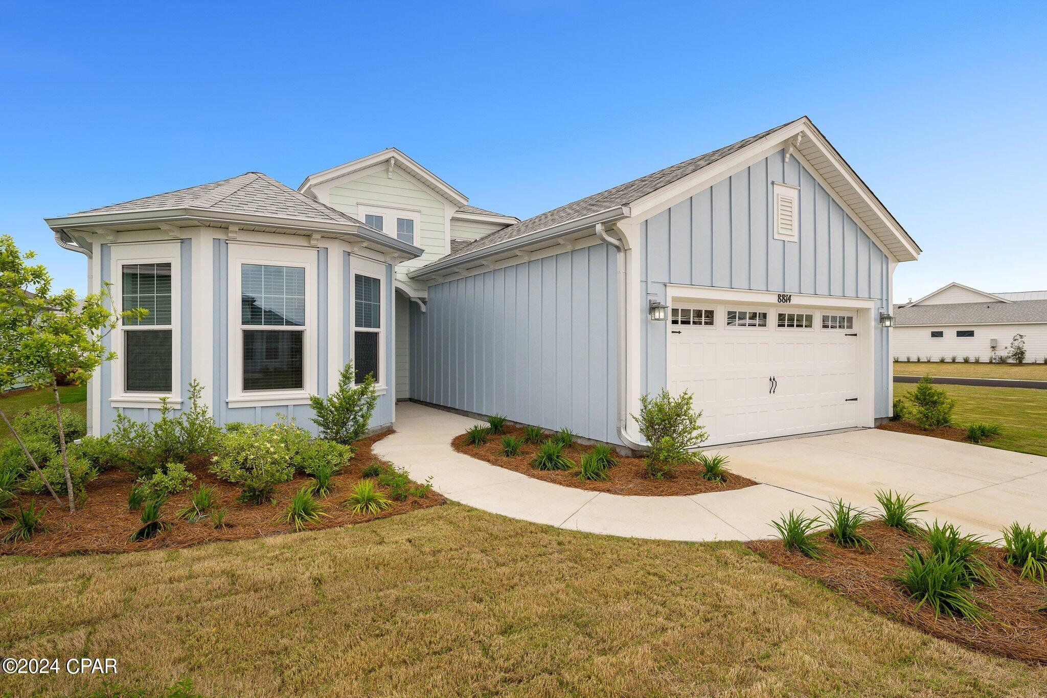 Light blue-gray home with white trim, a two-car garage, and landscaped front yard.