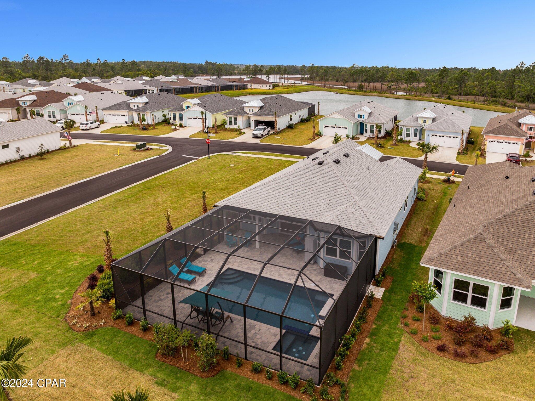 Aerial view of a home with a screened pool enclosure and landscaped yard.