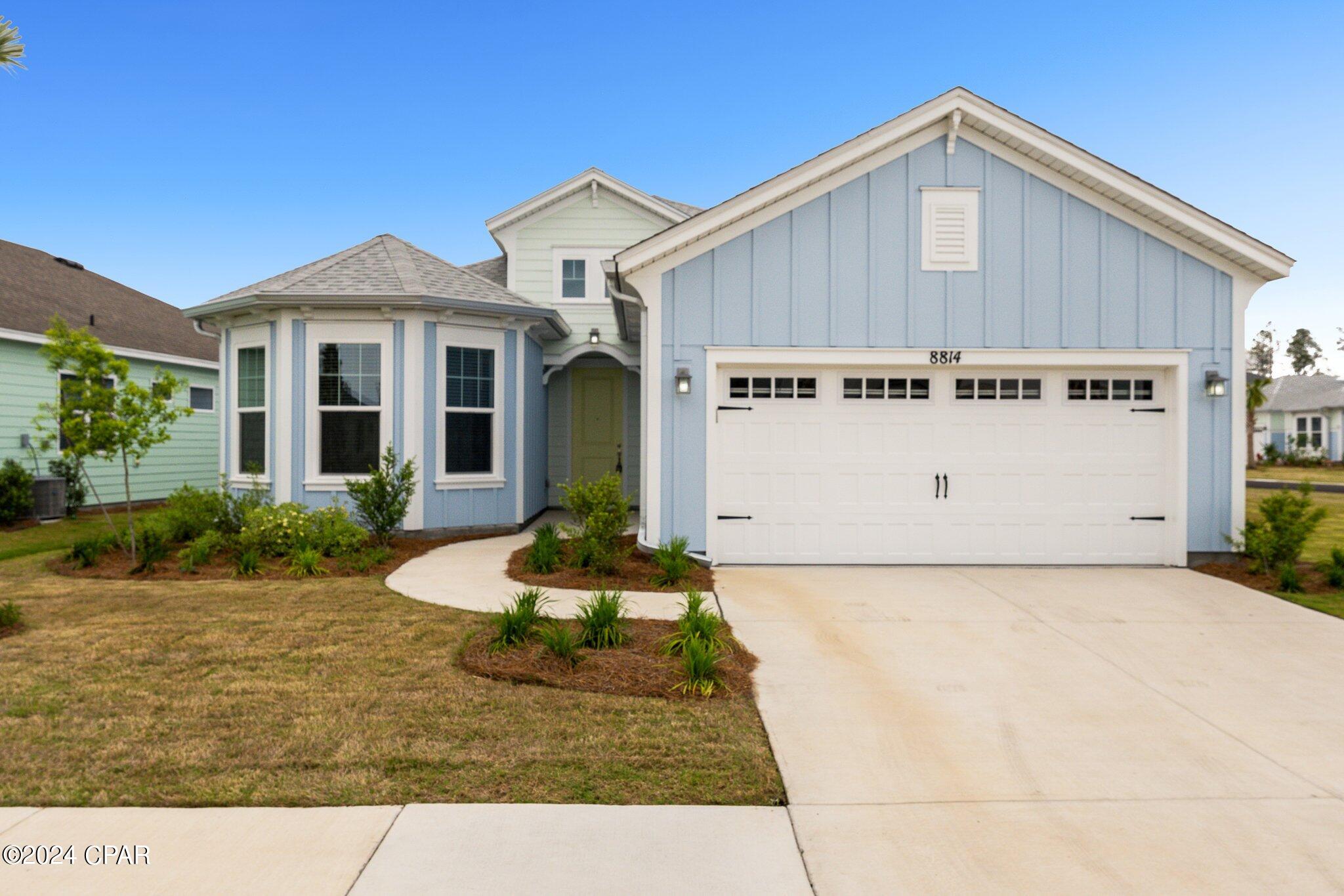 Light blue house with white trim, a two-car garage, and curved front walkway.