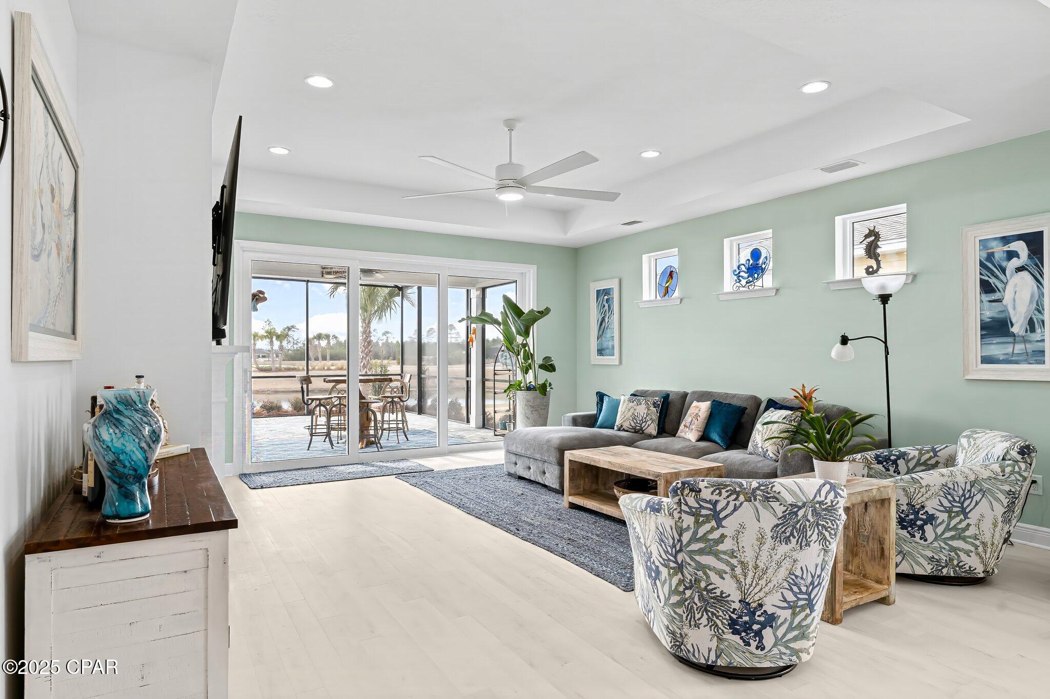 Living room with a gray sectional and patterned armchairs beside wide sliding glass doors.