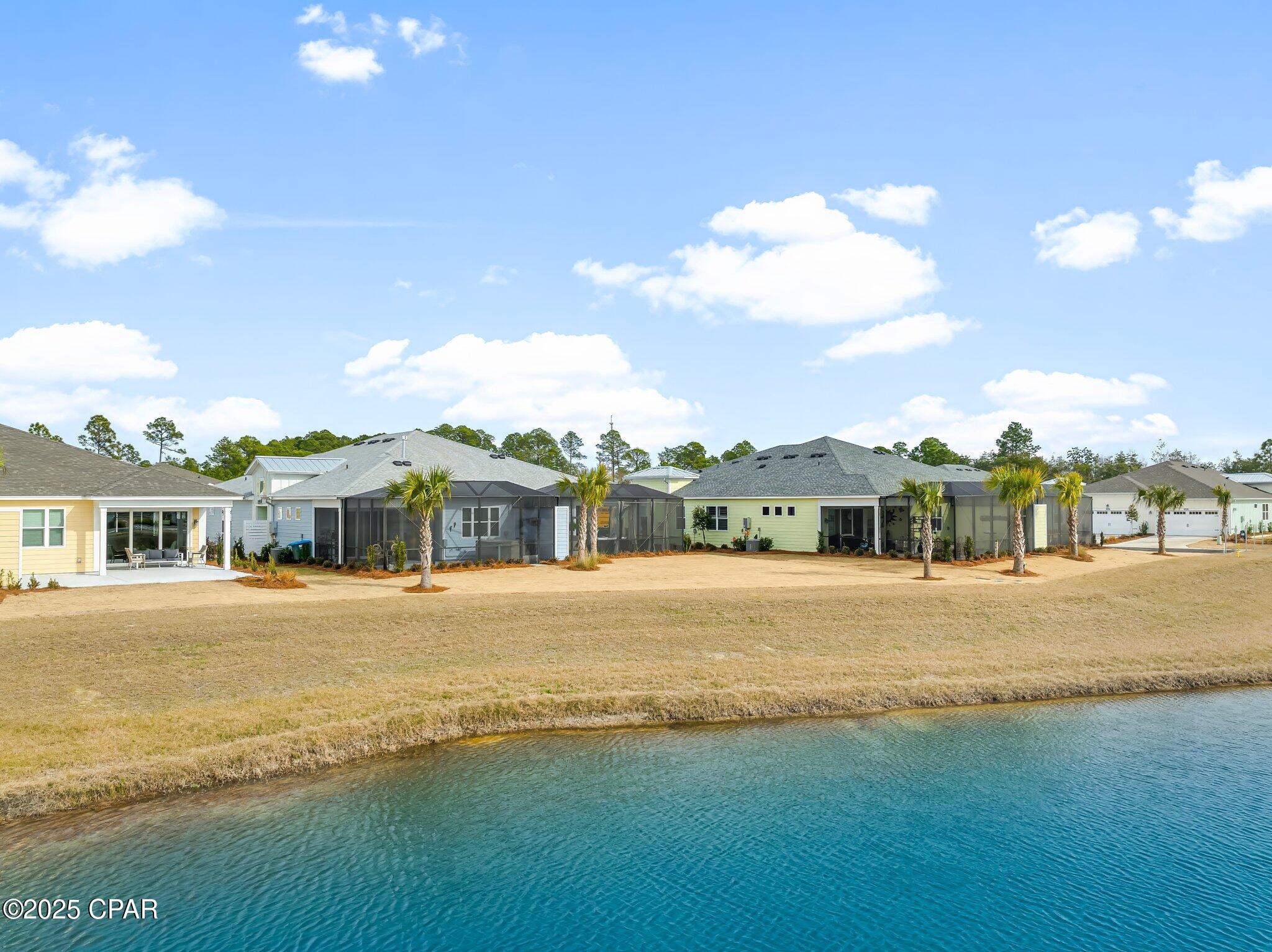 Single-story homes with screened lanais and palm trees line a turquoise canal.