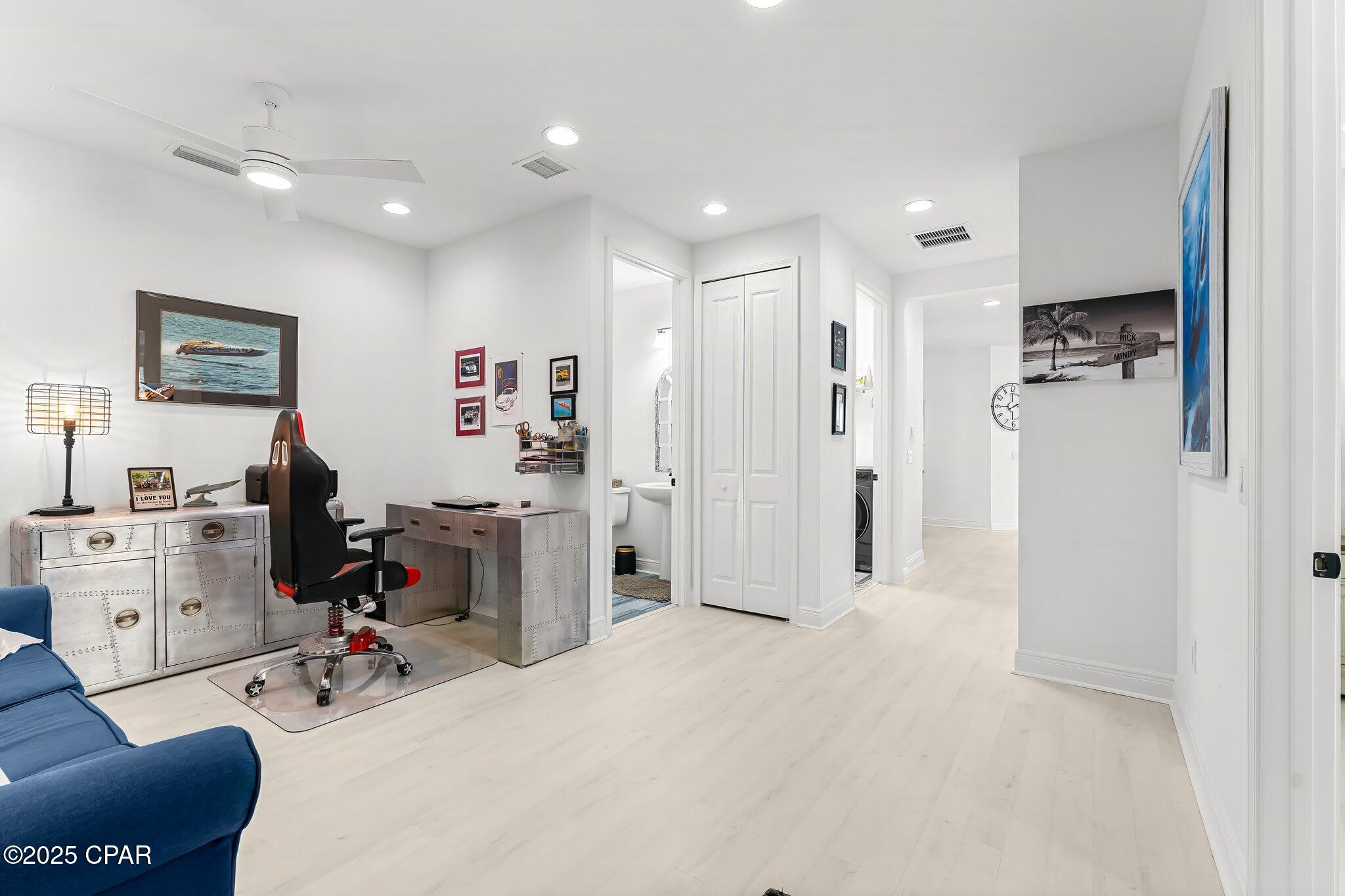 Furnished home office with a metallic desk, gaming chair, and blue sofa.