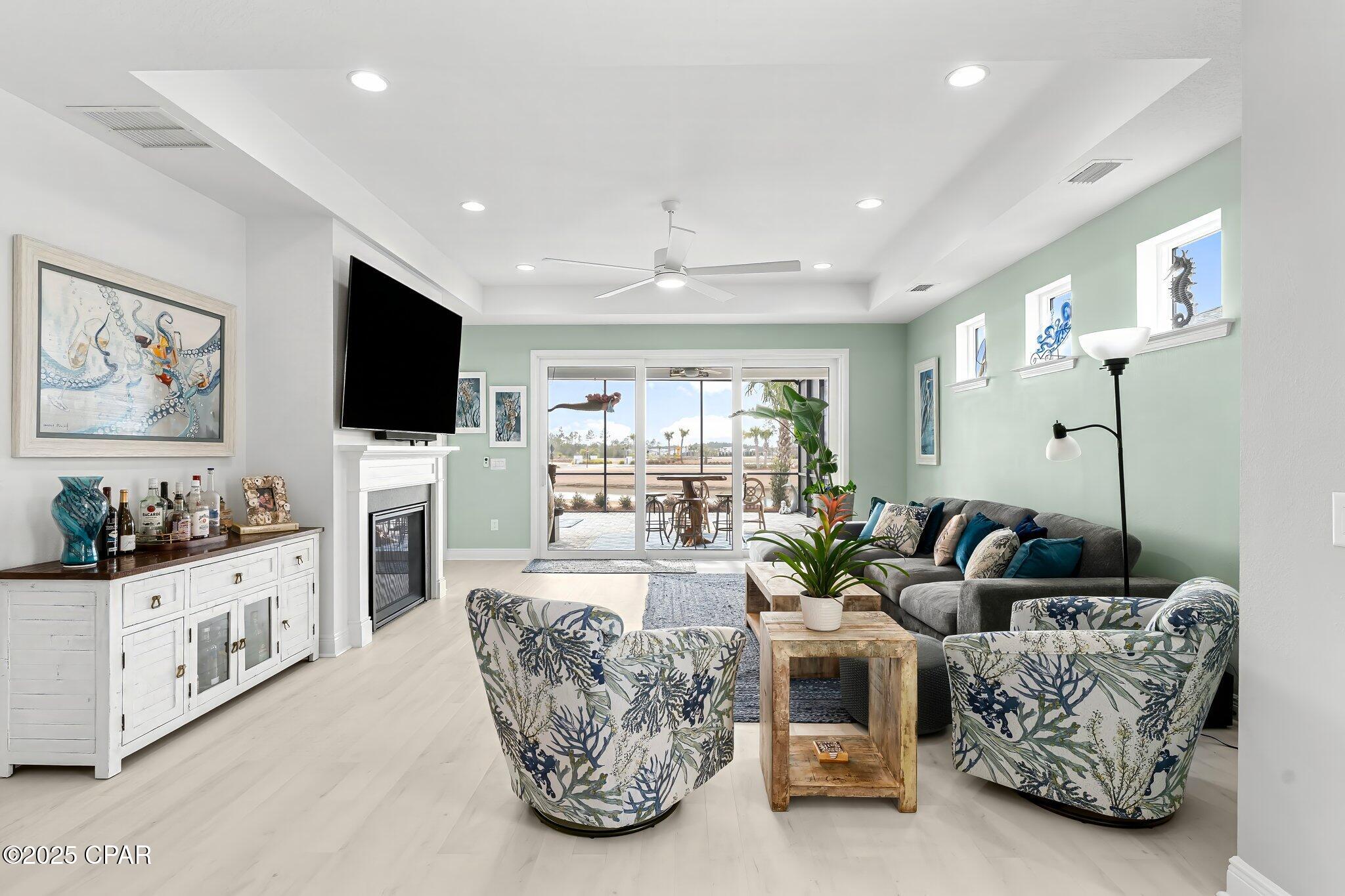 Furnished living room with a fireplace, patterned armchairs, and sliding doors to a patio.