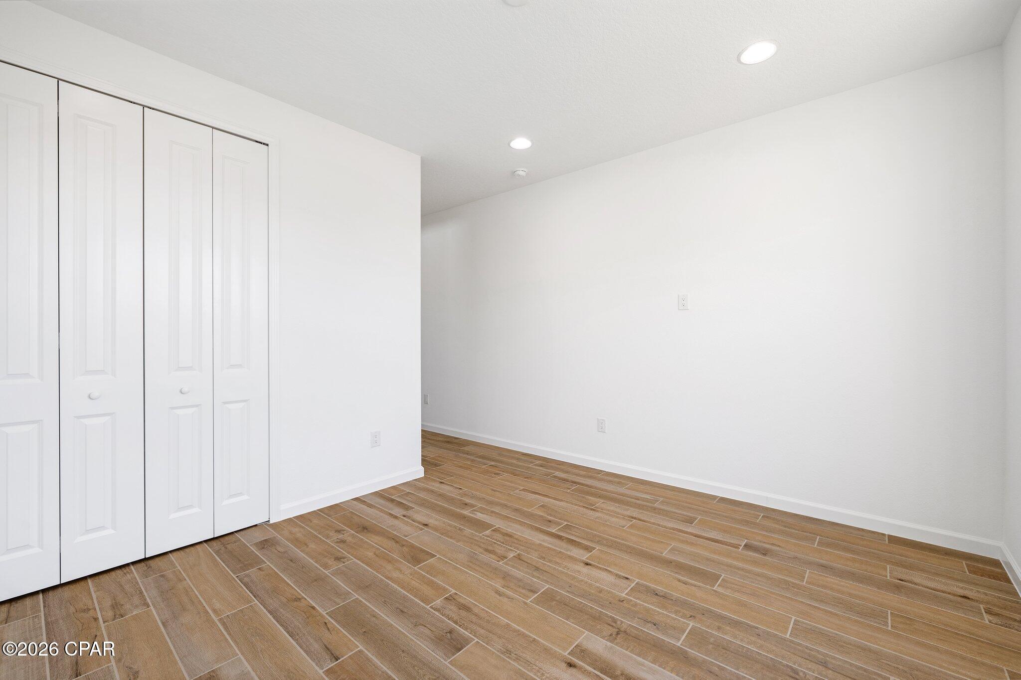 Empty room with folding closet doors and brown wood-look tile flooring
