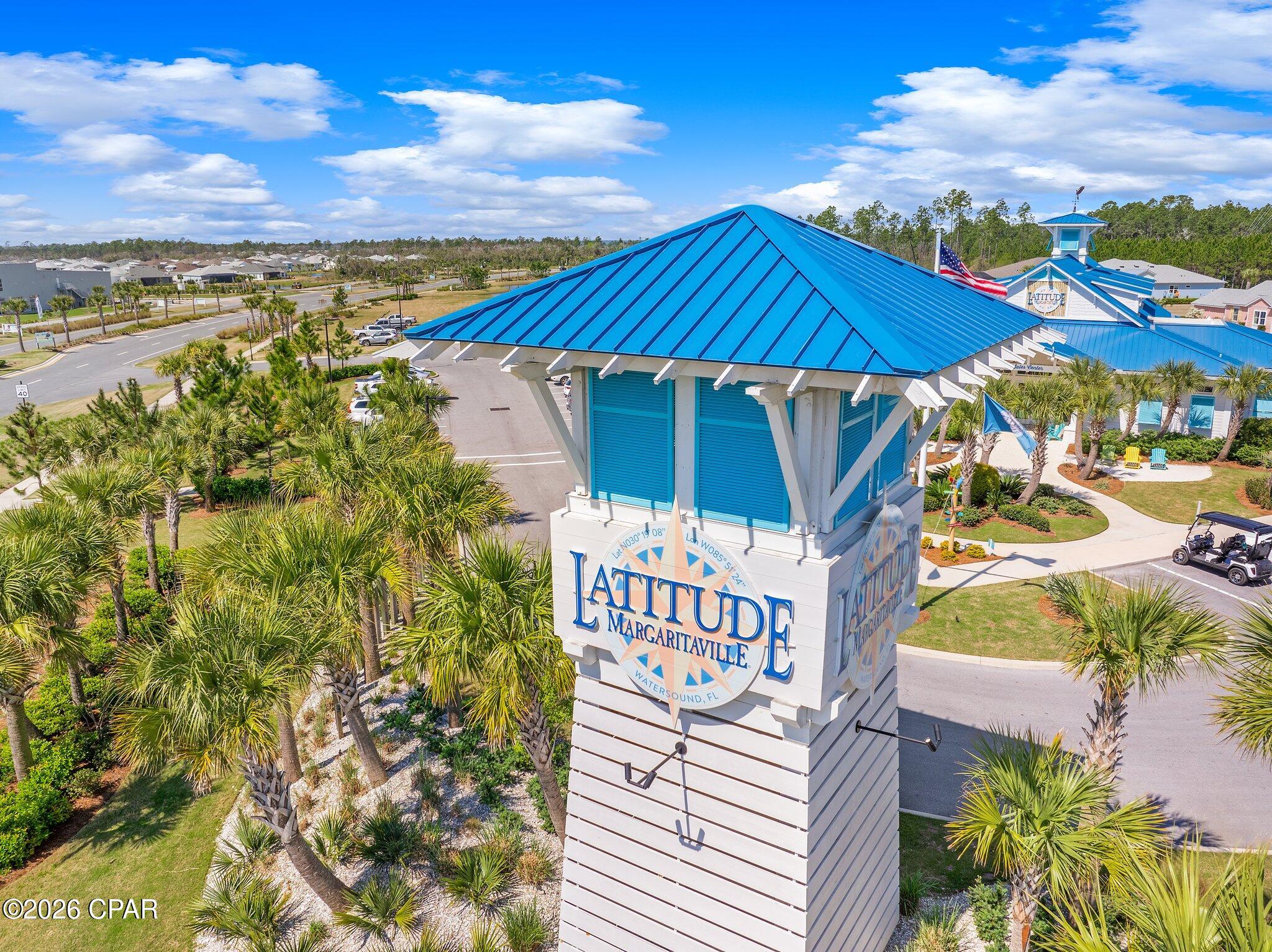Aerial view of the blue-roofed Latitude Margaritaville entrance sign among palm trees.