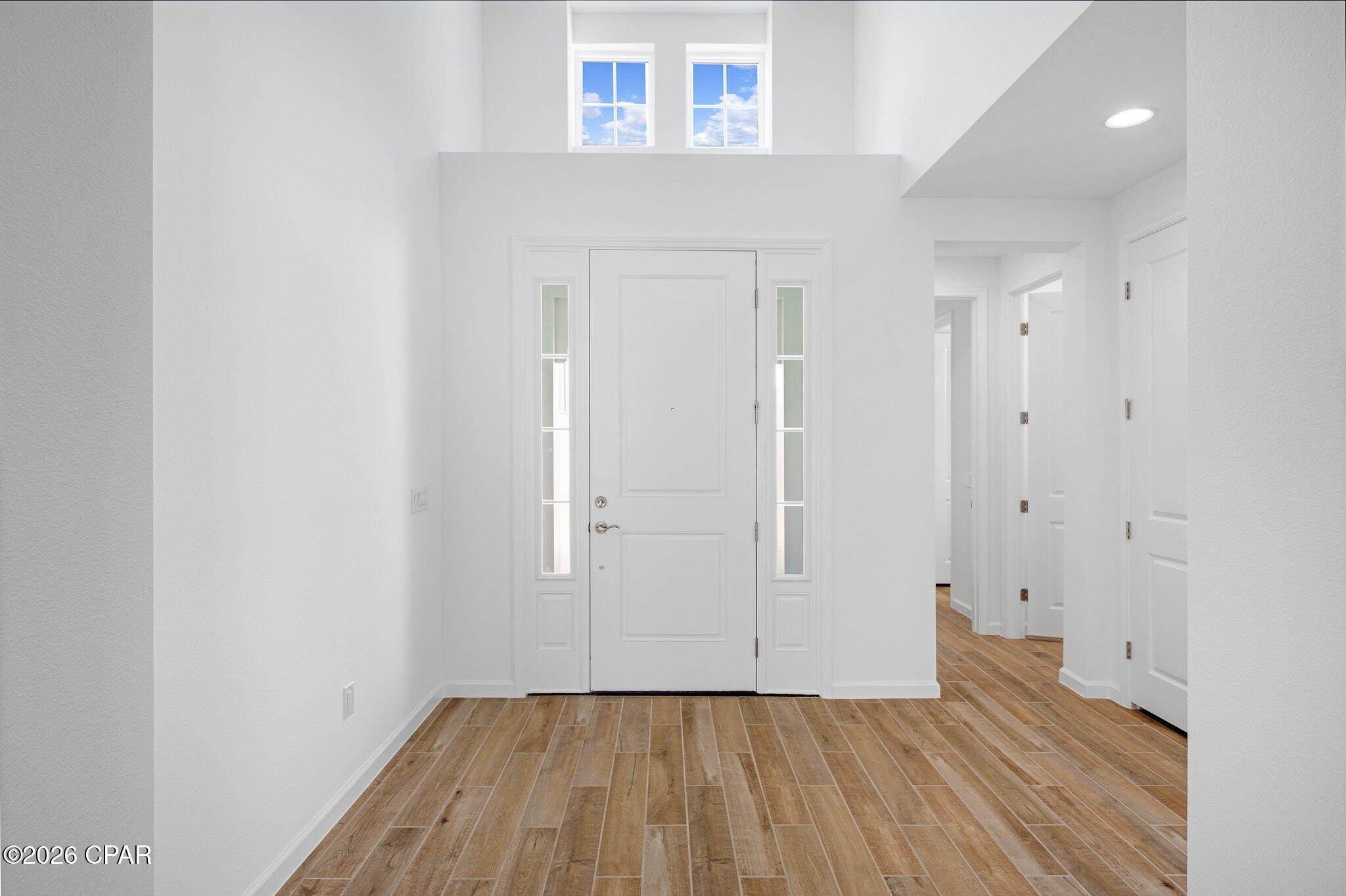 Entry foyer with a white front door, high windows, and wood-look tile flooring.