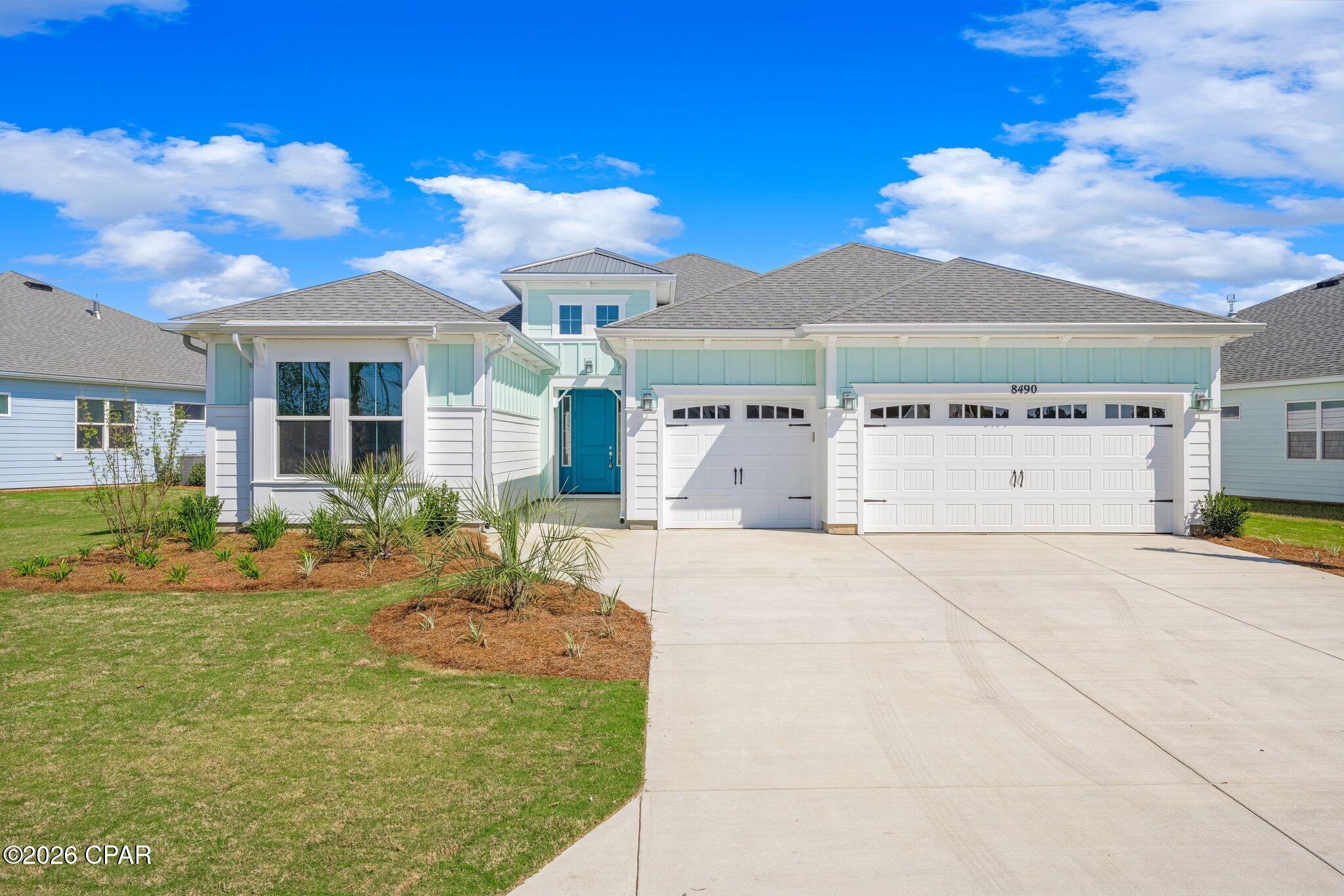 Aqua-and-white house with a teal front door, two garage doors, and a wide driveway.