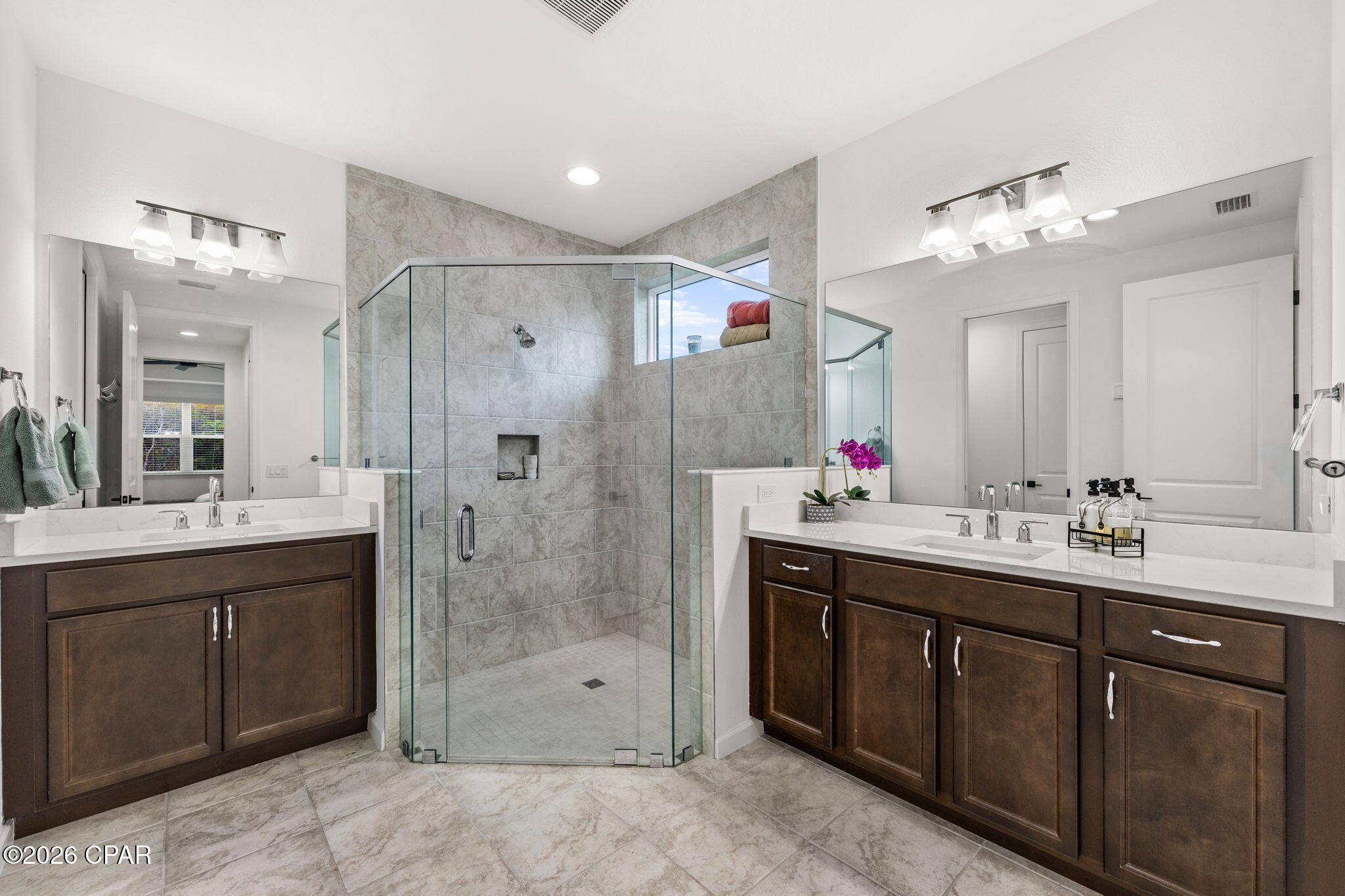 Bathroom with a glass walk-in shower and dark double vanity.