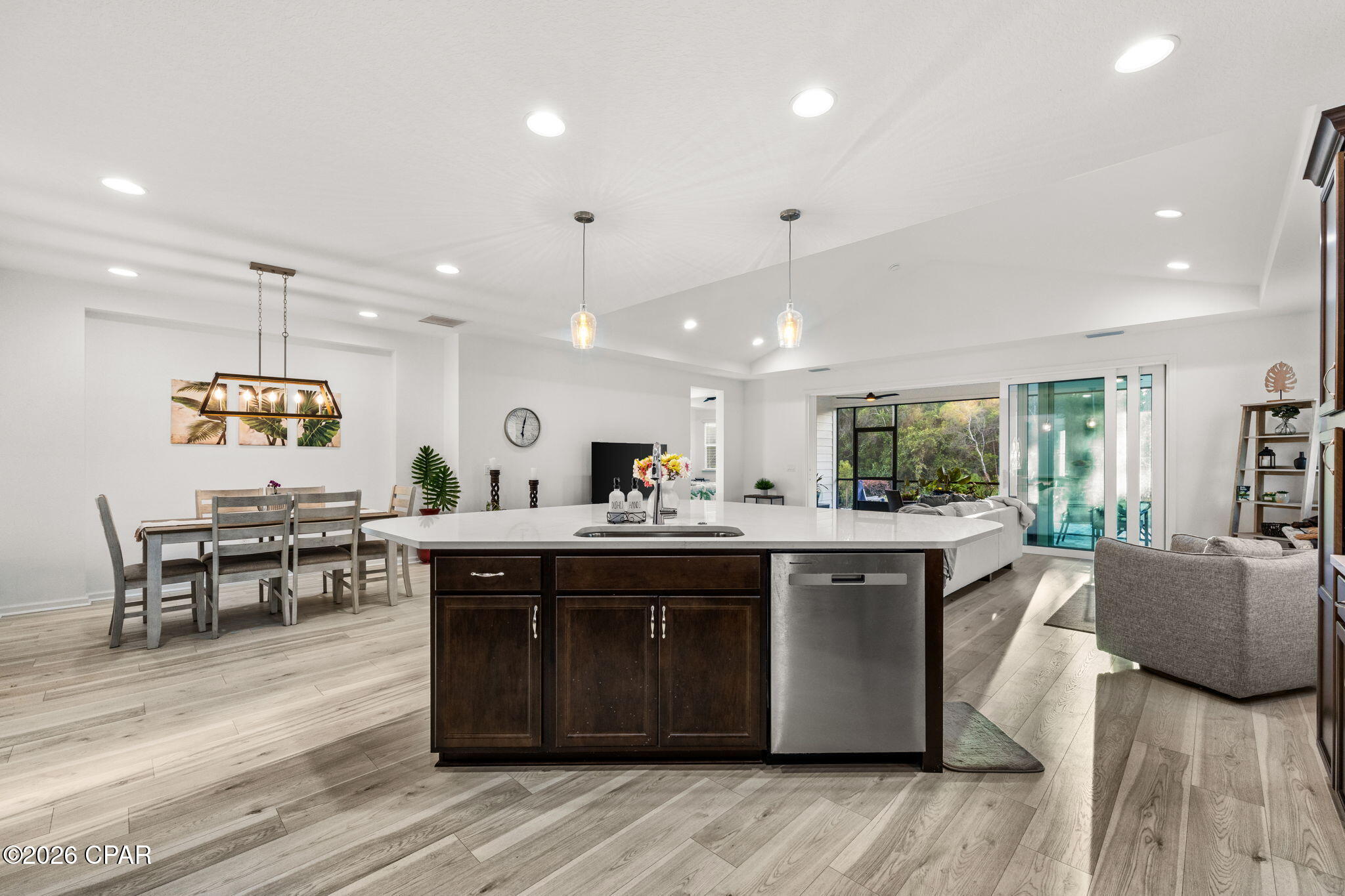 Open-plan kitchen with a large dark-wood island, dining area, and sliding doors to a screened patio.