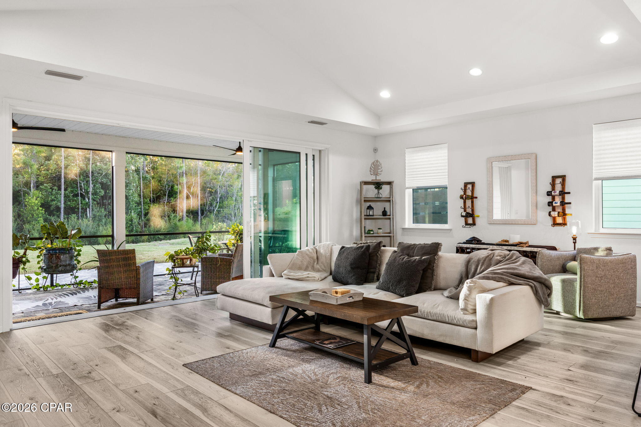 Furnished living room with a cream sectional and sliding glass doors overlooking a screened patio.
