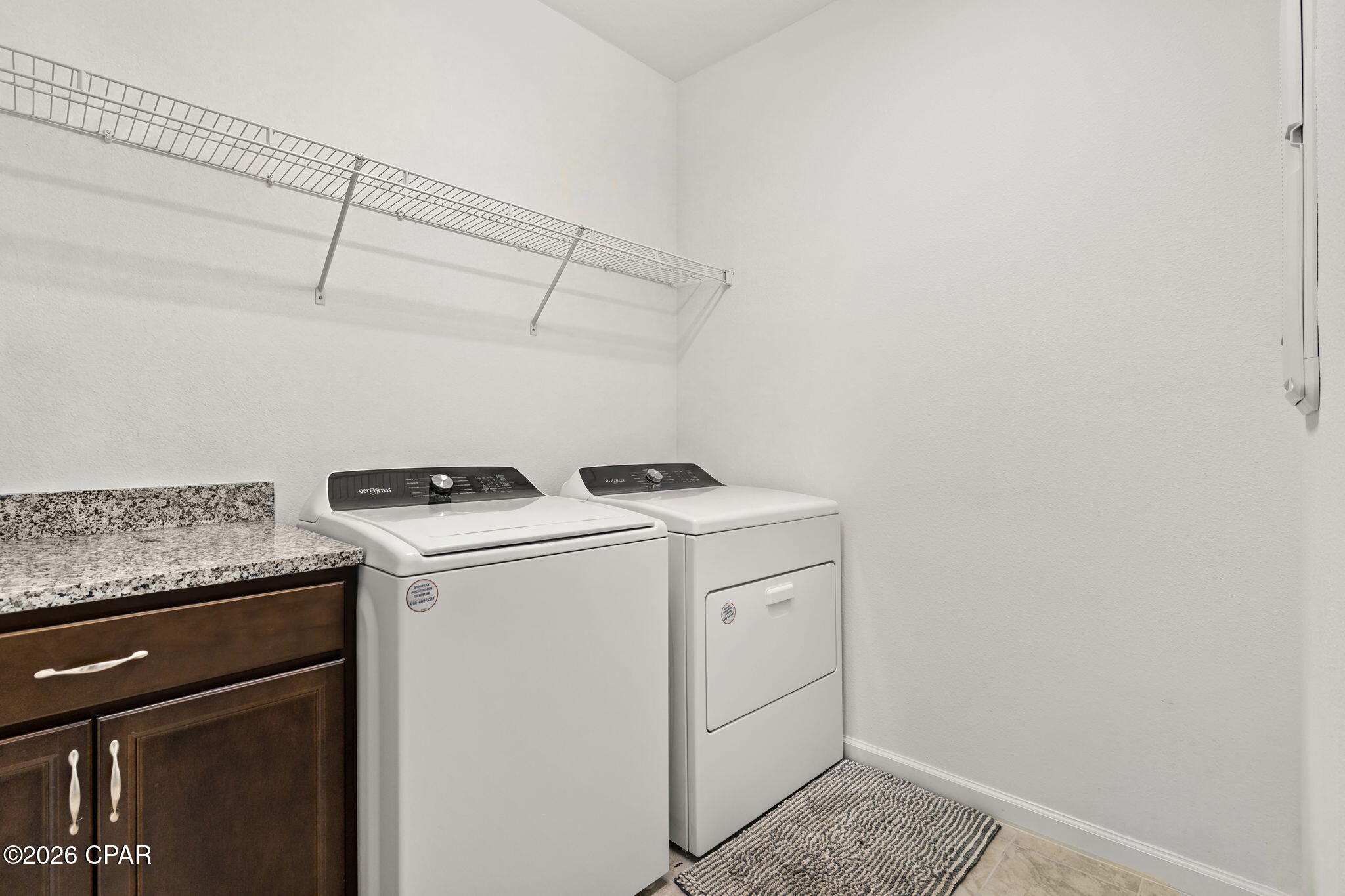 Laundry room with a washer and dryer beside dark wood cabinets and a granite countertop.