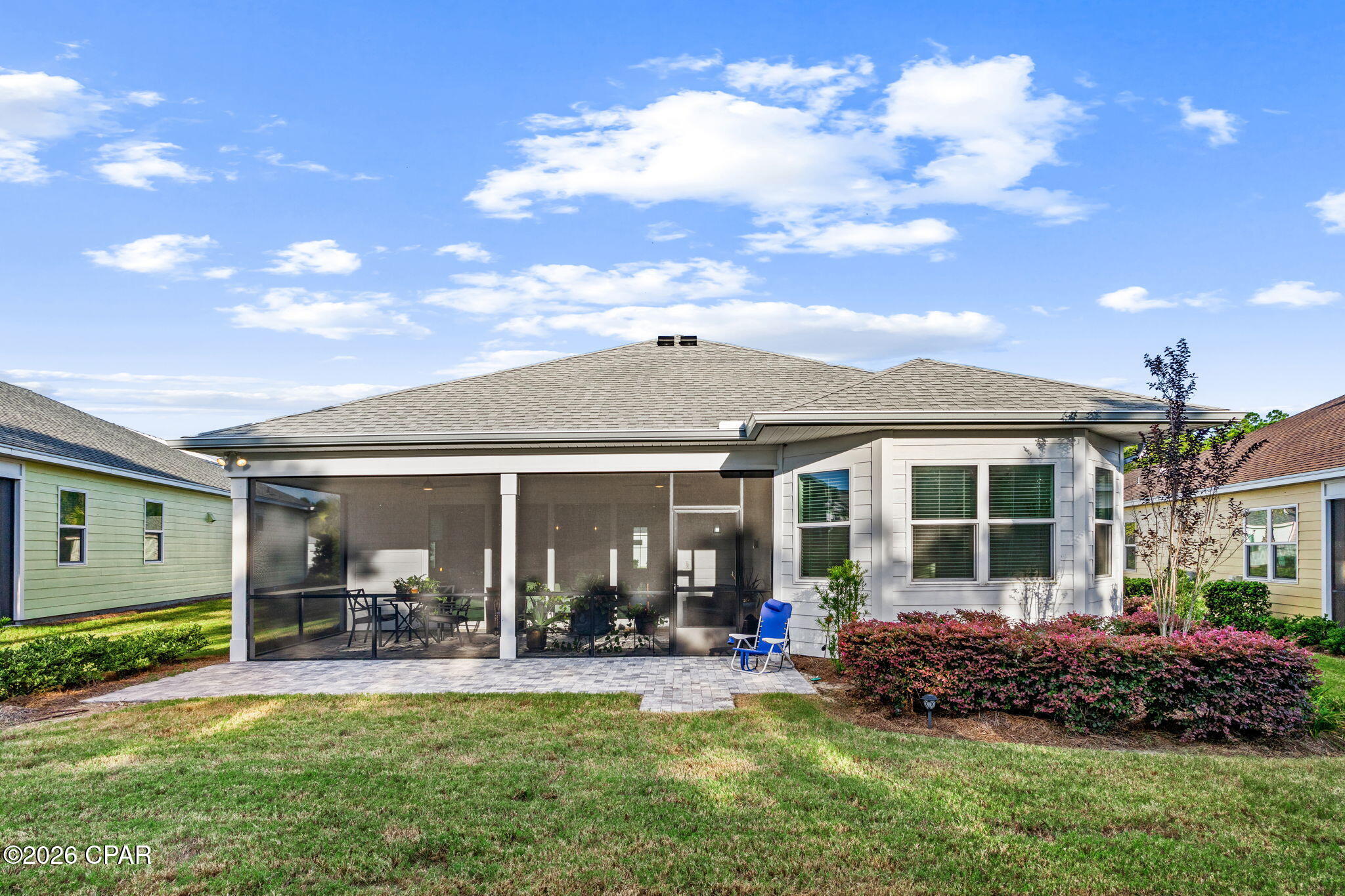 House rear with a screened patio, paved terrace, and landscaped lawn.
