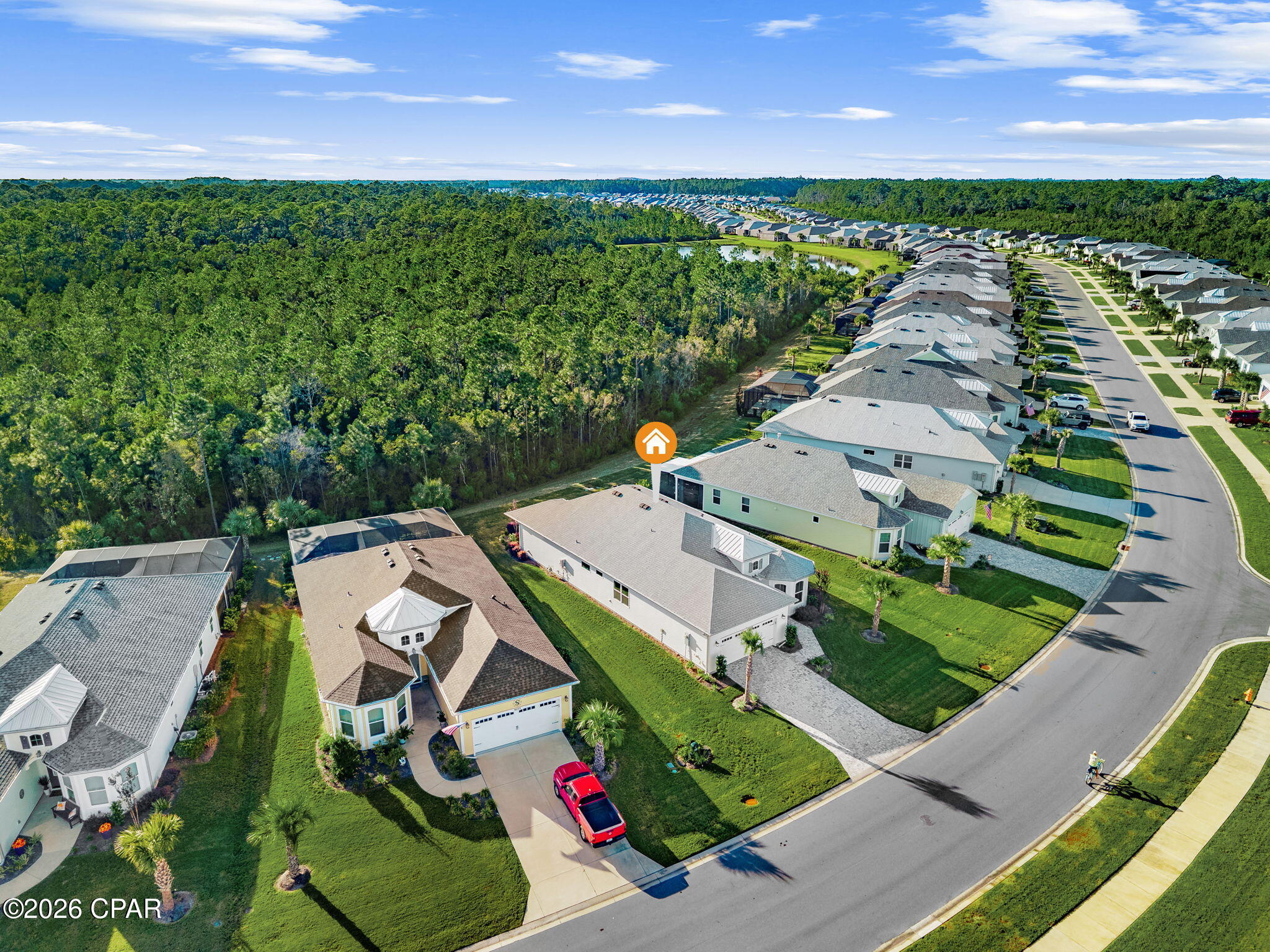 Aerial view of 9259 Paradise Drive beside a wooded area and rows of neighboring homes.