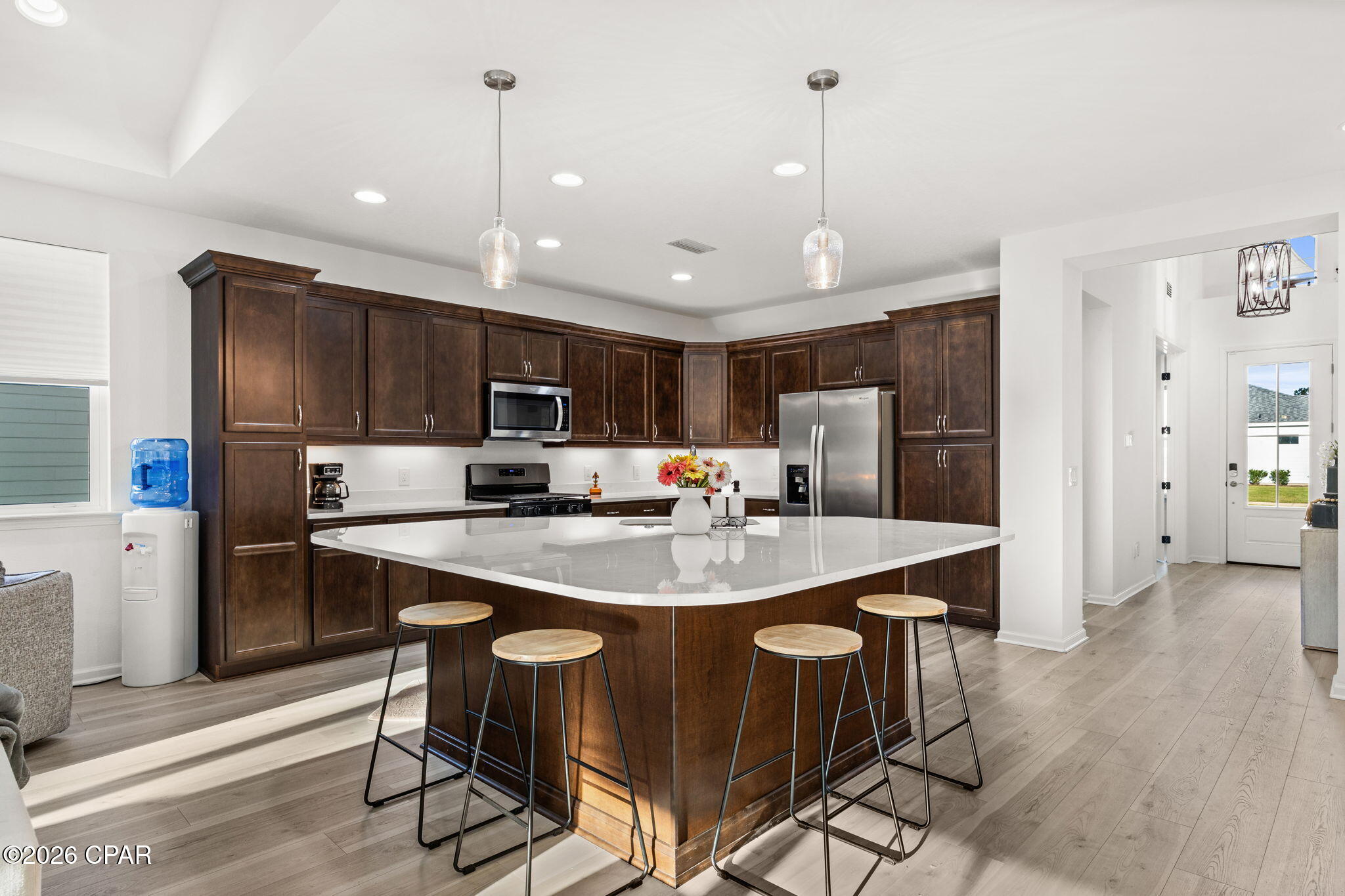 Kitchen with dark wood cabinets, stainless appliances, and a large island with four stools.