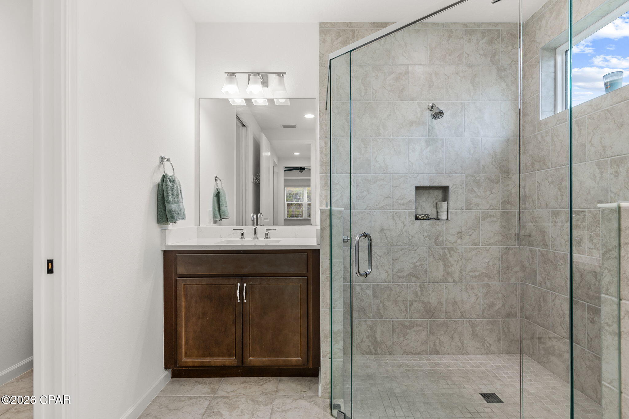 Bathroom with dark wood vanity and spacious glass-enclosed tiled shower.