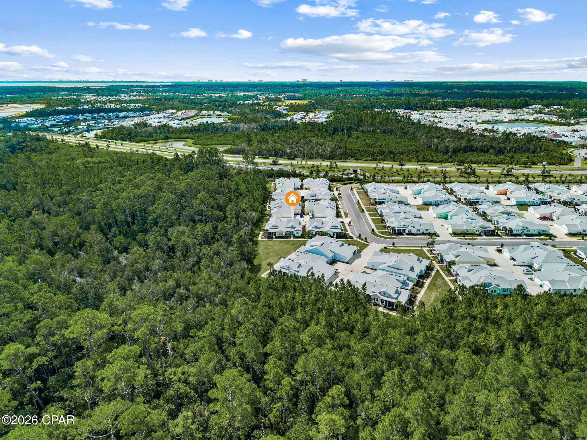 Aerial view of a home in a neighborhood bordering dense woodland, marked by an orange house icon.